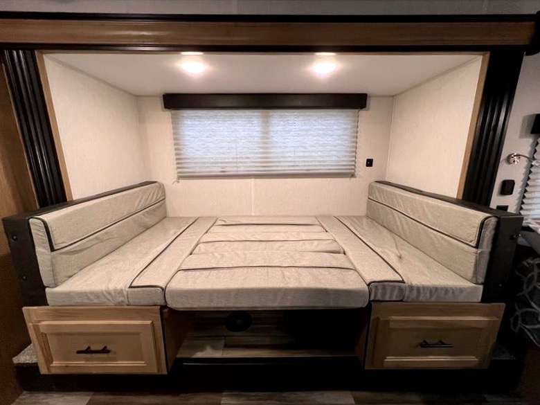 Inside an RV rental: a flexible dinette converts to a spacious bed with under-seat storage drawers.. Forest River Cherokee Wolf Pup 17JGBL 2023