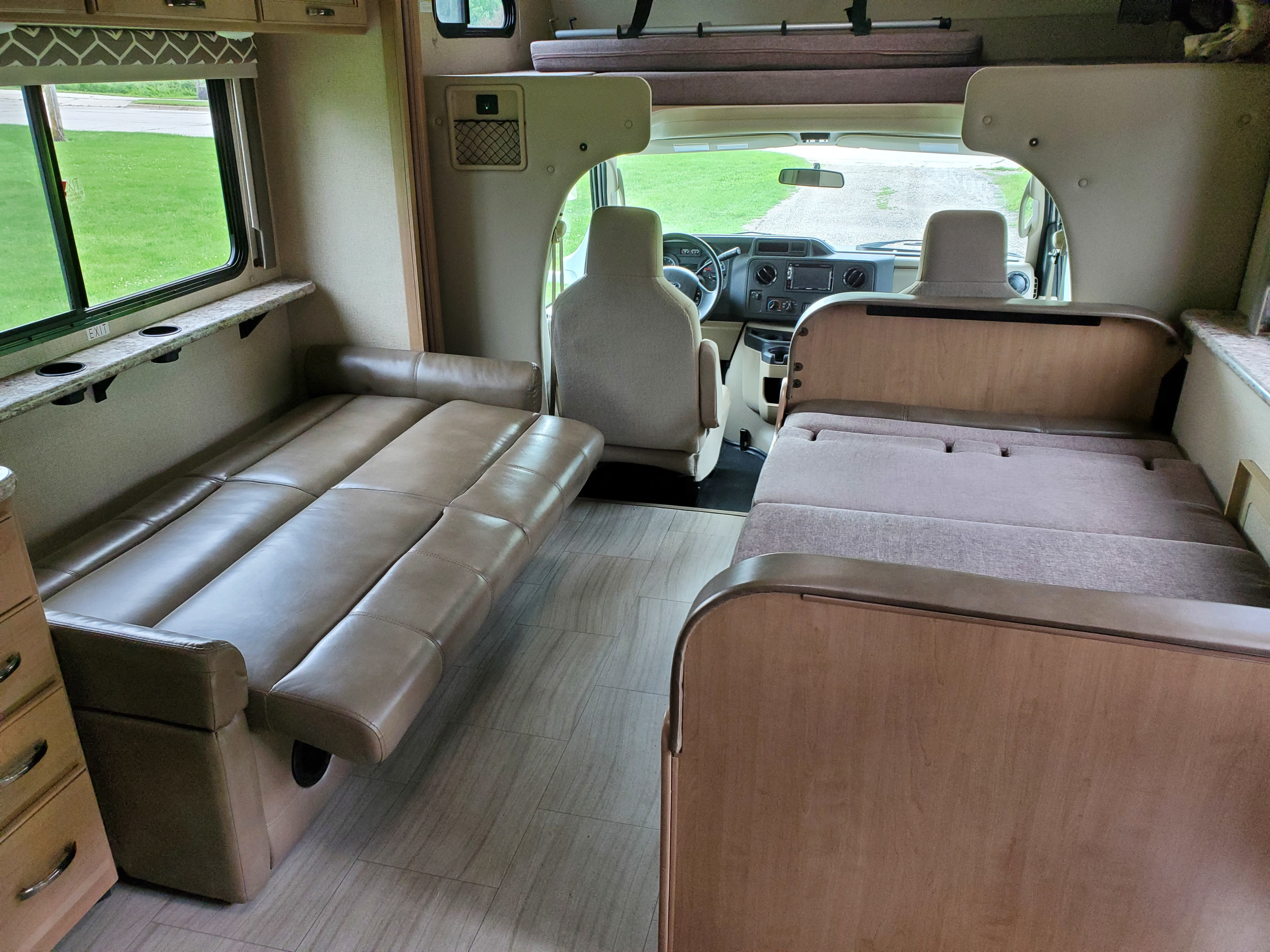 Inside this clean rv rental, a neutral-toned interior shows a sofa on the left and a dinette on the right, leading to the cabin.. Thor Motor Coach Daybreak 30D 2020