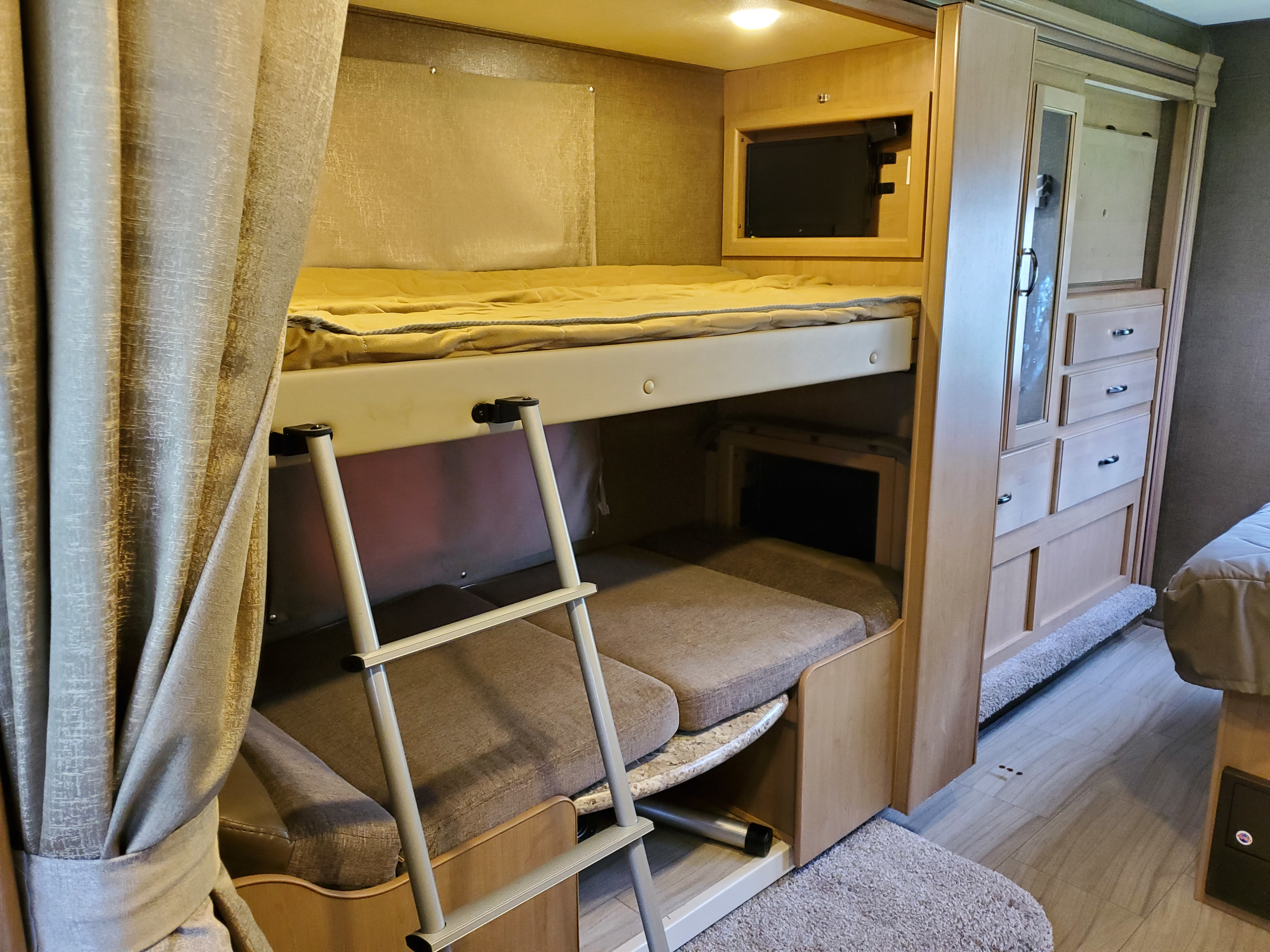 This RV rental features bunk beds with a ladder, built-in TV, and cabinetry, providing practical and comfortable living space.. Thor Motor Coach Daybreak 30D 2020