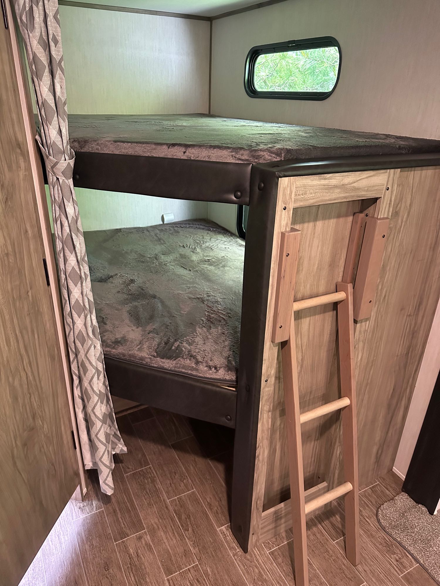Cozy bunk beds in an RV rental, complete with a privacy curtain, window, and ladder for accessibility. Ideal for families.. Forest River Cherokee Alpha Wolf 2022