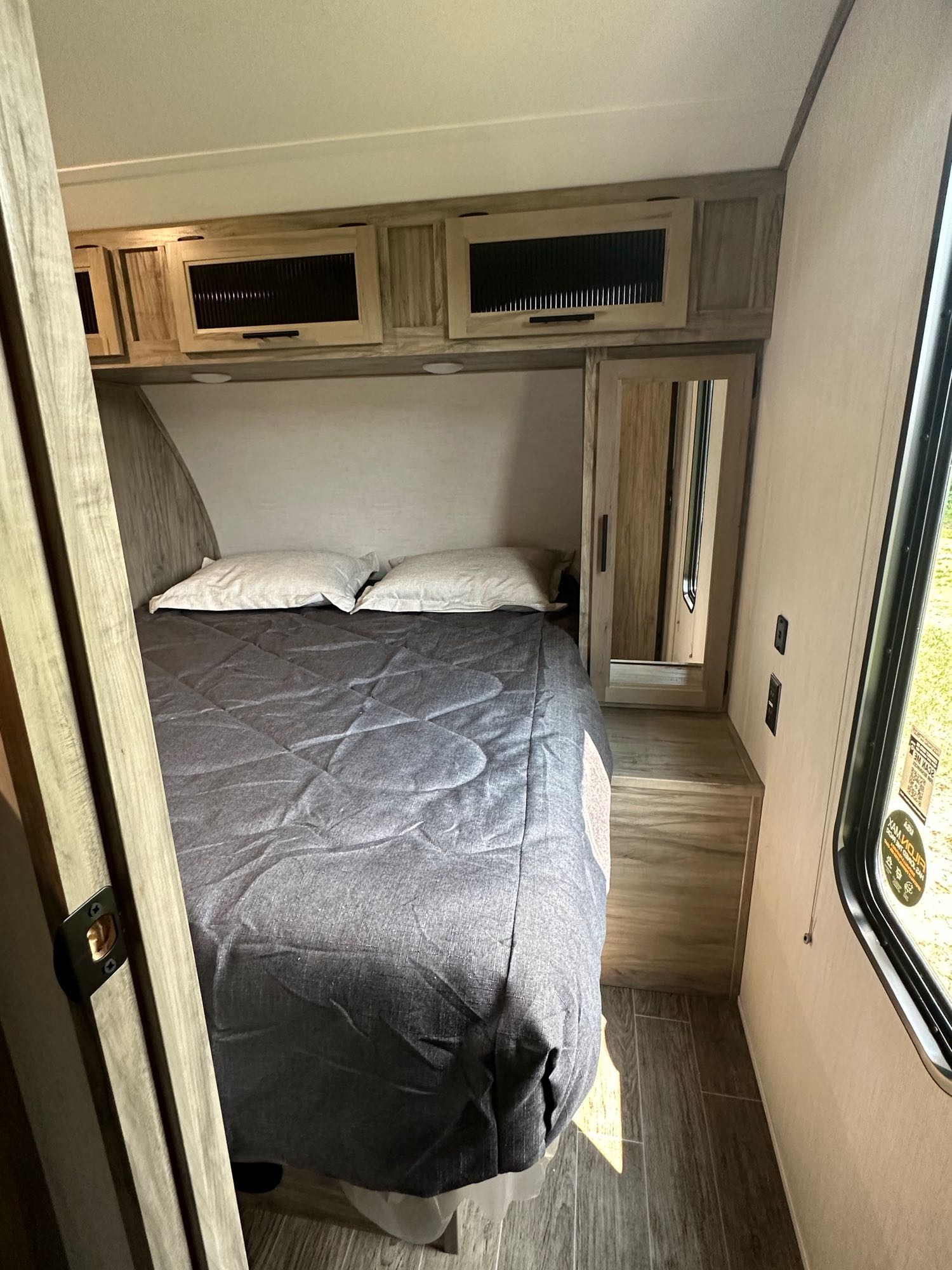 Cozy RV rental bedroom featuring a comfortable bed, overhead storage, and mirrored closet for your adventures.. Forest River Cherokee Alpha Wolf 2022