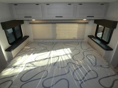 RV rental: Bright RV bedroom with a new, plastic-covered mattress, overhead cabinets, and windows.. Coachmen Freelander 29KB 2023