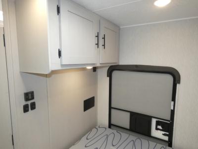 RV rental interior: Light gray cabinets, under-cabinet light, control panel, and compact bed area.. Coachmen Freelander 22XG 2023