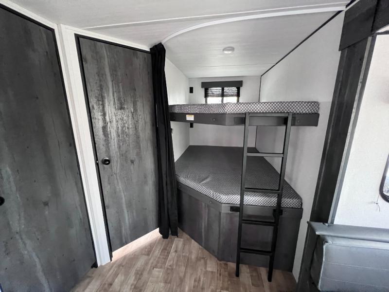 Modern RV rental interior featuring dark wood-look bunk beds with ladder & soft mattresses for comfortable sleeping.. Keystone RV Hideout 2023