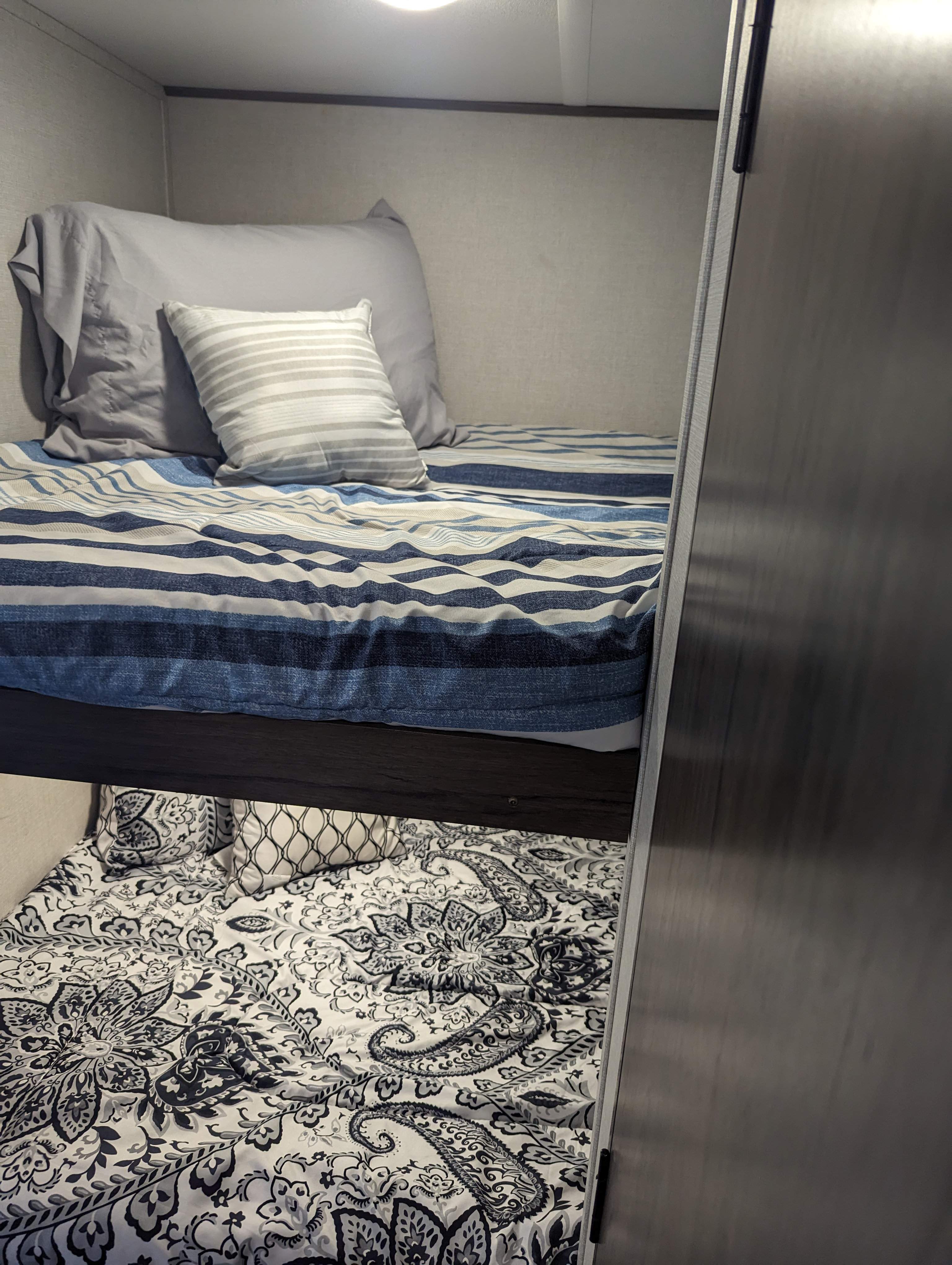 Cozy bunk beds with striped and paisley bedding inside an RV rental, offering comfortable sleeping arrangements for travel.. Avenger 26bk 2021