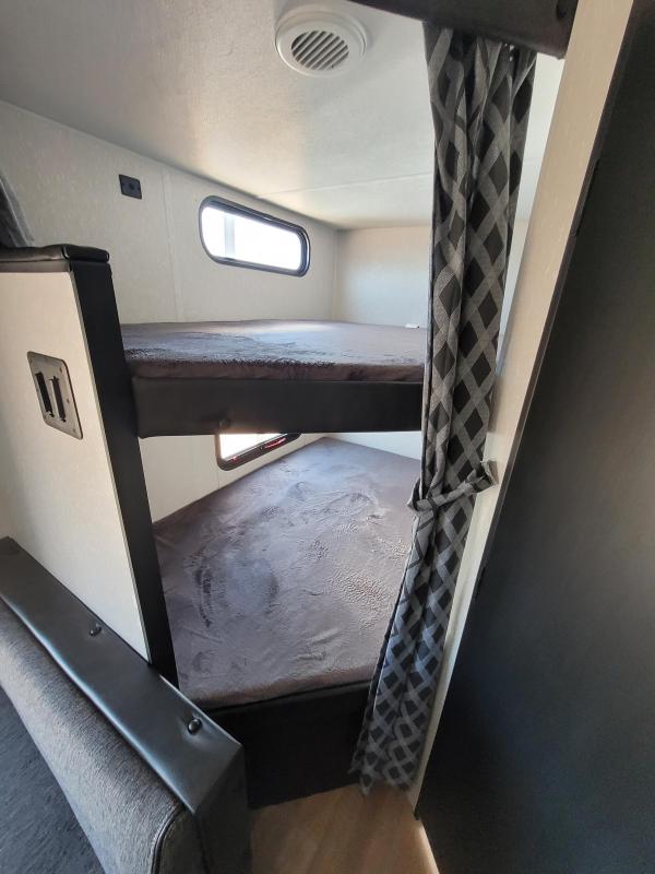 RV rental interior: Two cozy bunk beds with dark bedding, small window, and privacy curtain. Ideal for family travel.. Forest River Cherokee Grey Wolf Special Edition 2022