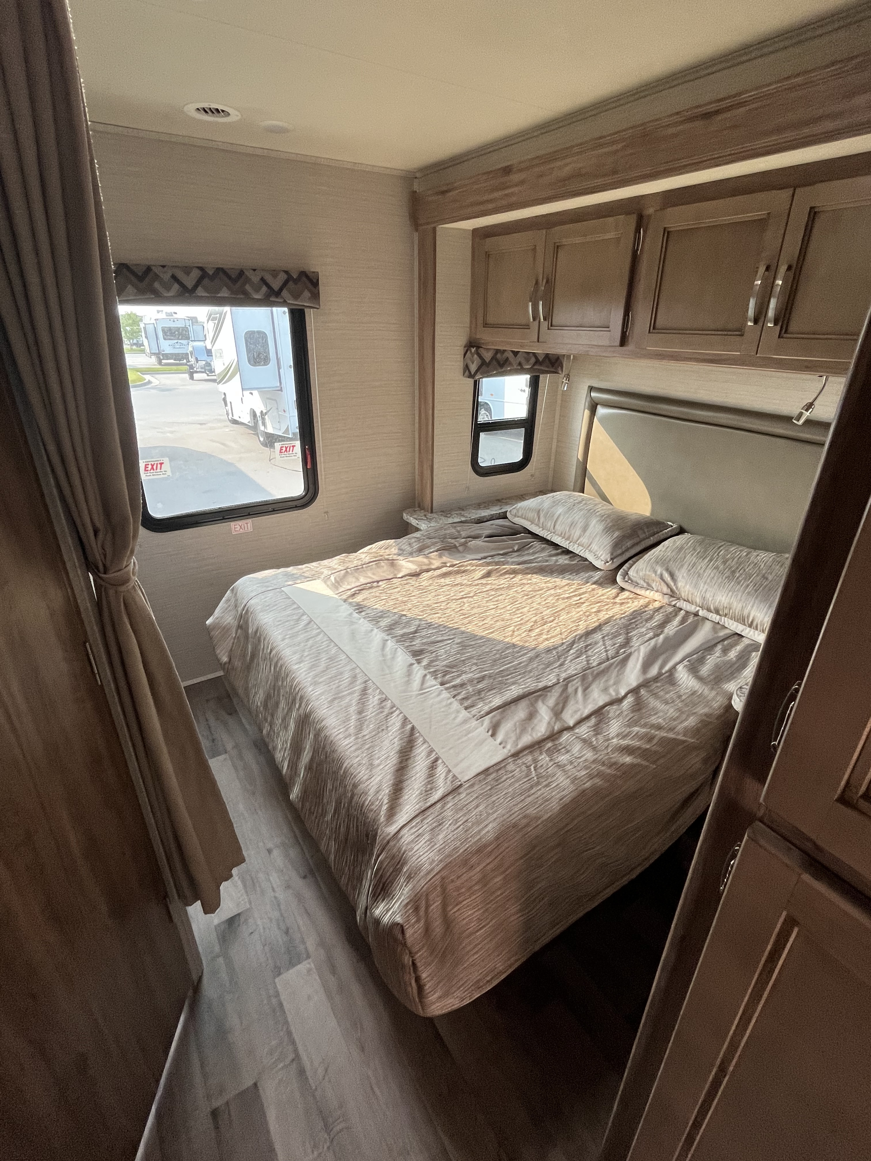 Cozy RV bedroom for your next RV rental adventure. Features a comfortable bed, overhead cabinets, and bright windows.. Jayco Redhawk SE 2020