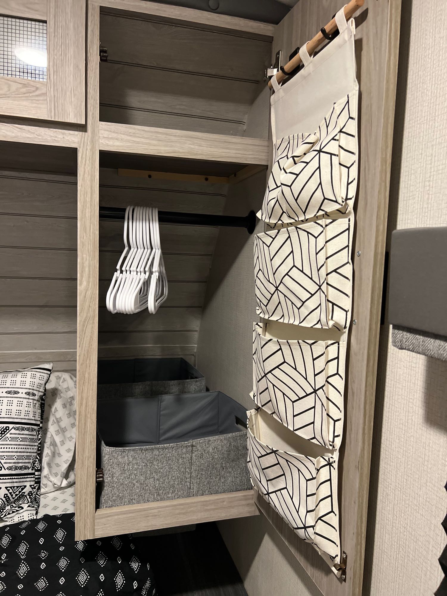 Efficient RV rental storage: Closet with hangers, bins, & a geometric-patterned fabric organizer provides smart organization.. Keystone RV Passport GT 2022