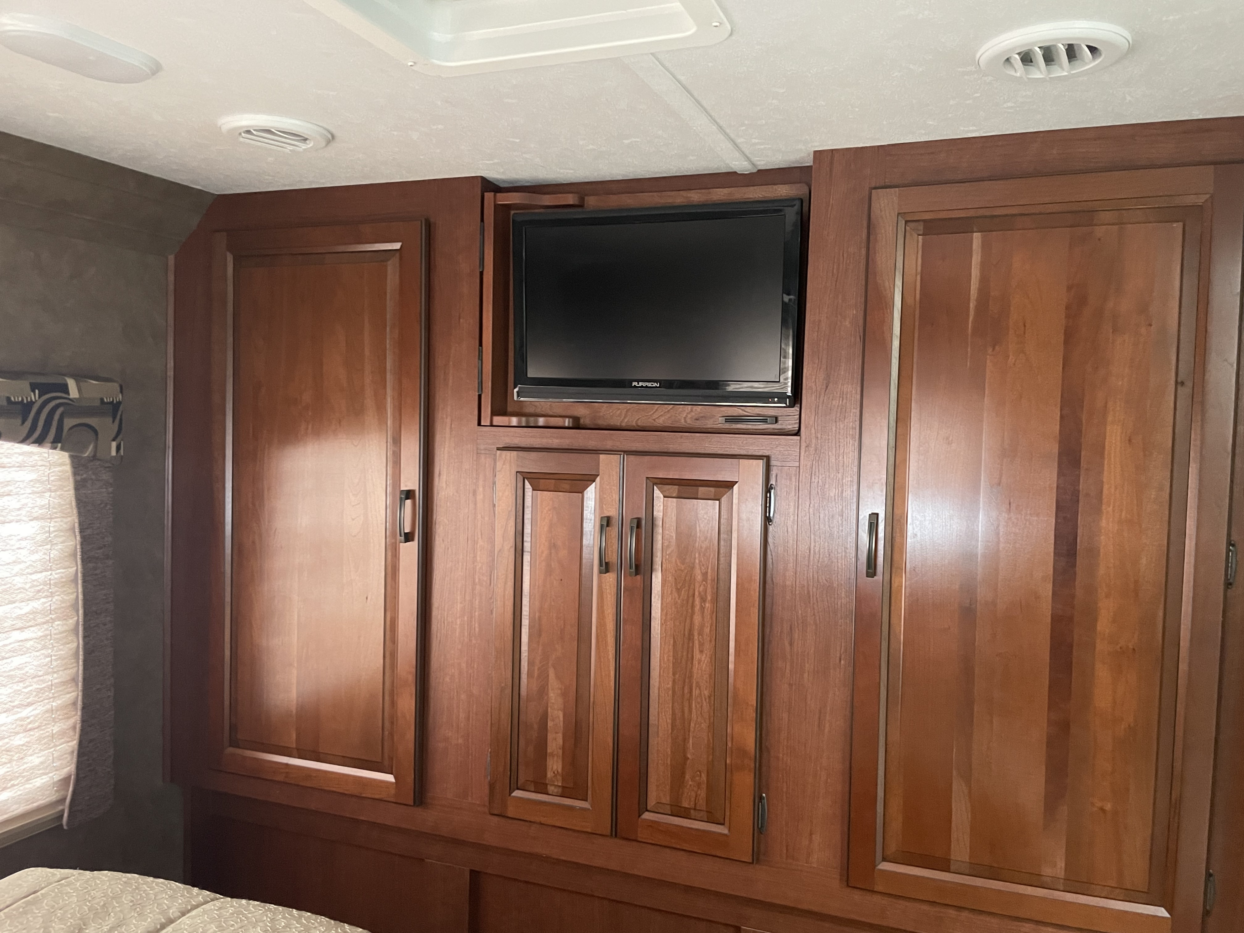 Bedroom wall in an RV rental, featuring built-in wooden cabinets, an integrated TV, and storage space.. Forest River Sunseeker 2016