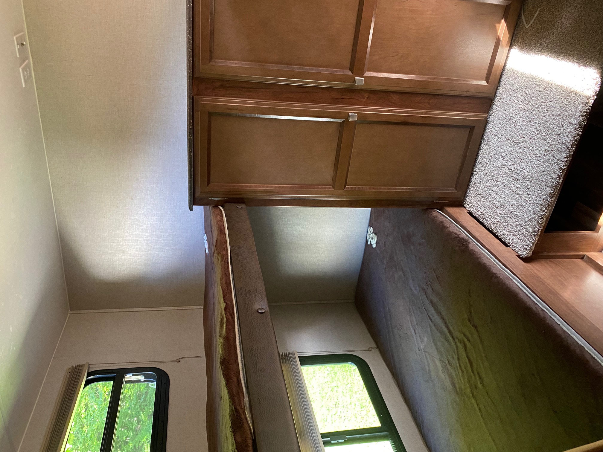 Interior view of an RV rental, featuring stacked bunk beds, wooden cabinets, and a window for comfortable travel.. Coachmen Freedom Express 2020