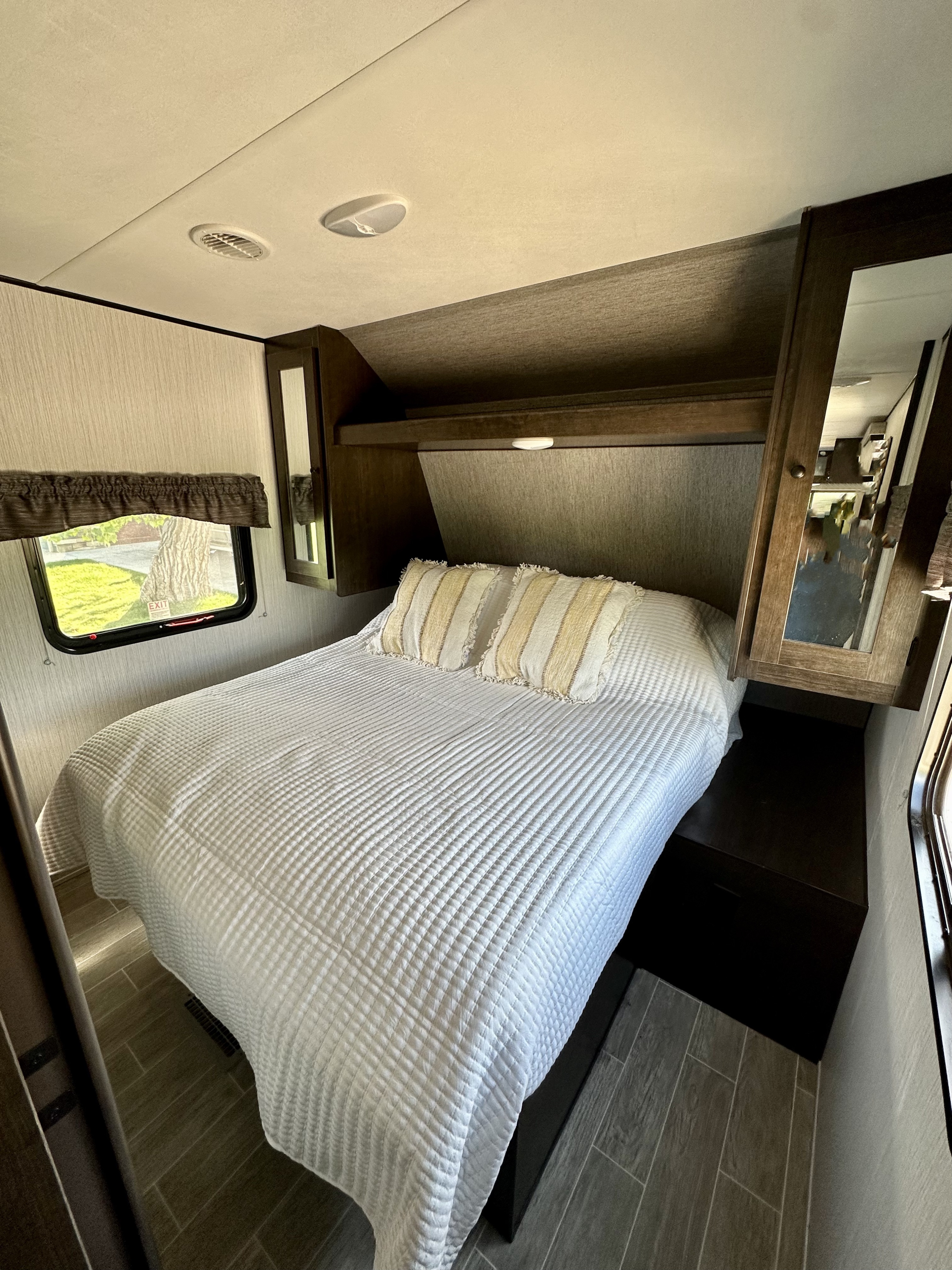 Cozy RV rental bedroom with a comfy bed, overhead storage, and window views. Perfect for travel!. Heartland RVs Trail Runner 2021