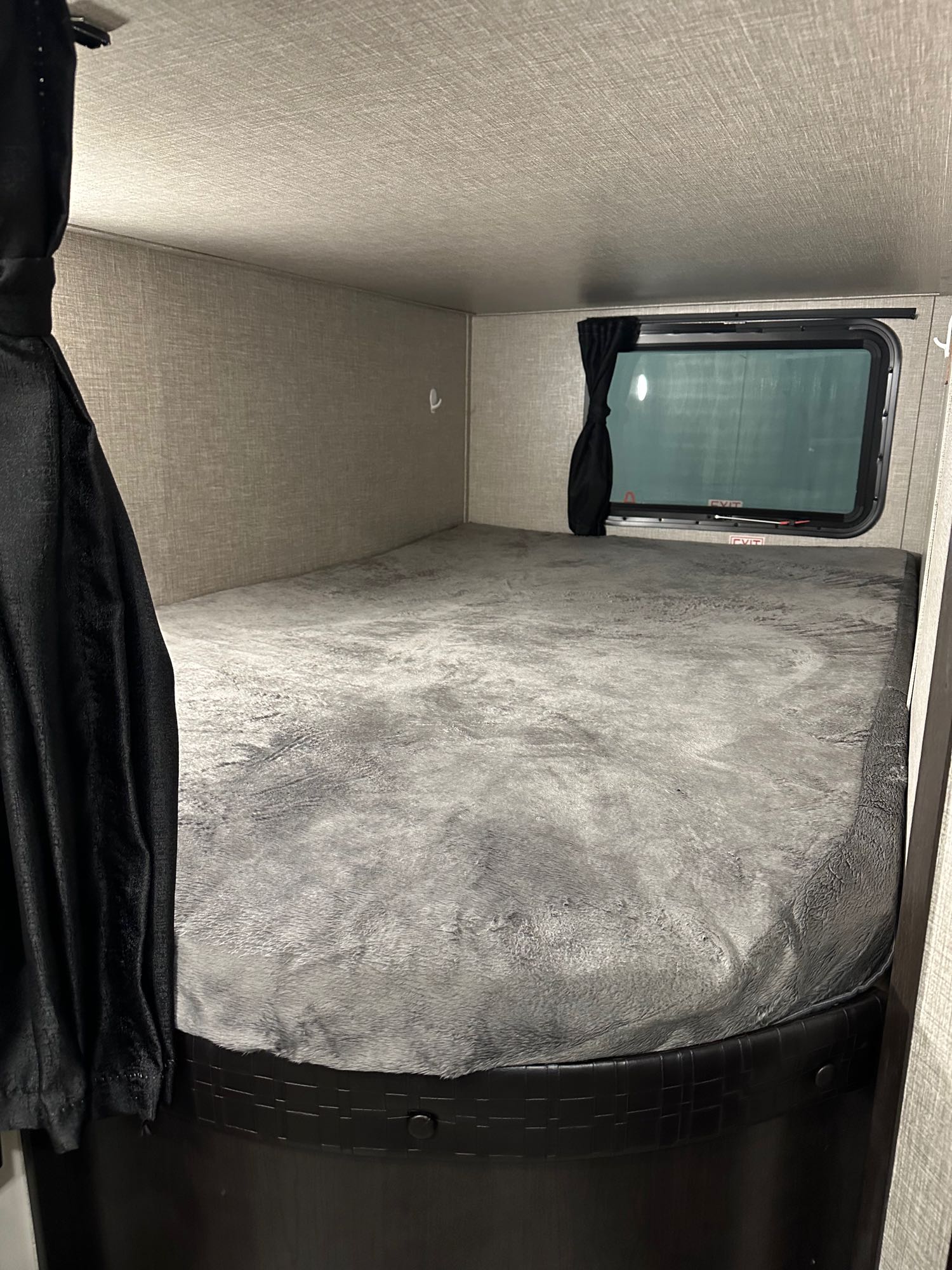 Cozy RV rental bunk bed with a soft grey blanket and curtained window, perfect for comfortable travel.. Jayco Jay Flight SLX 2022