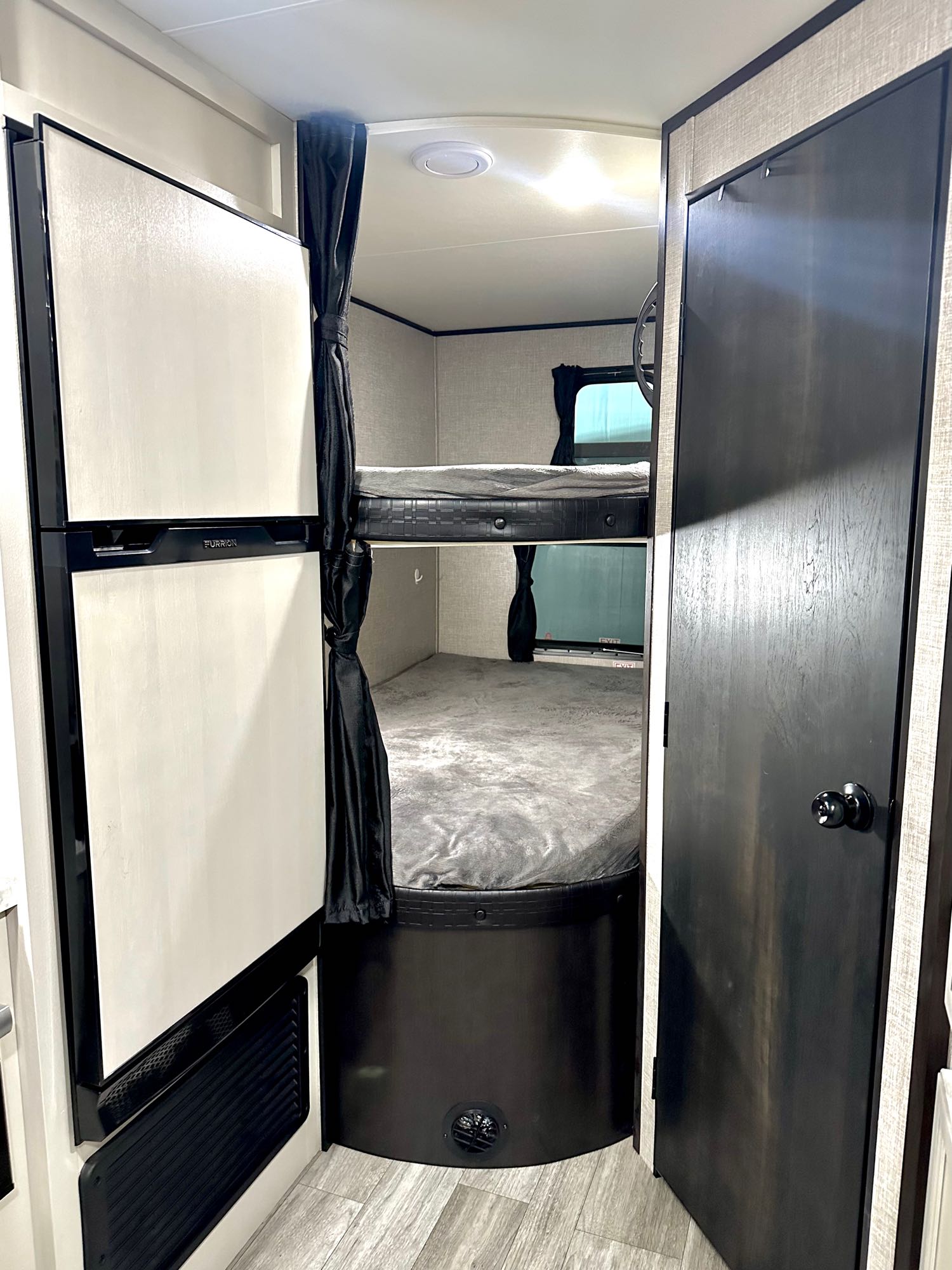 This RV rental interior shows a bunkhouse with two beds, a refrigerator, and a privacy door, ideal for family camper adventures.. Jayco Jay Flight SLX 2022