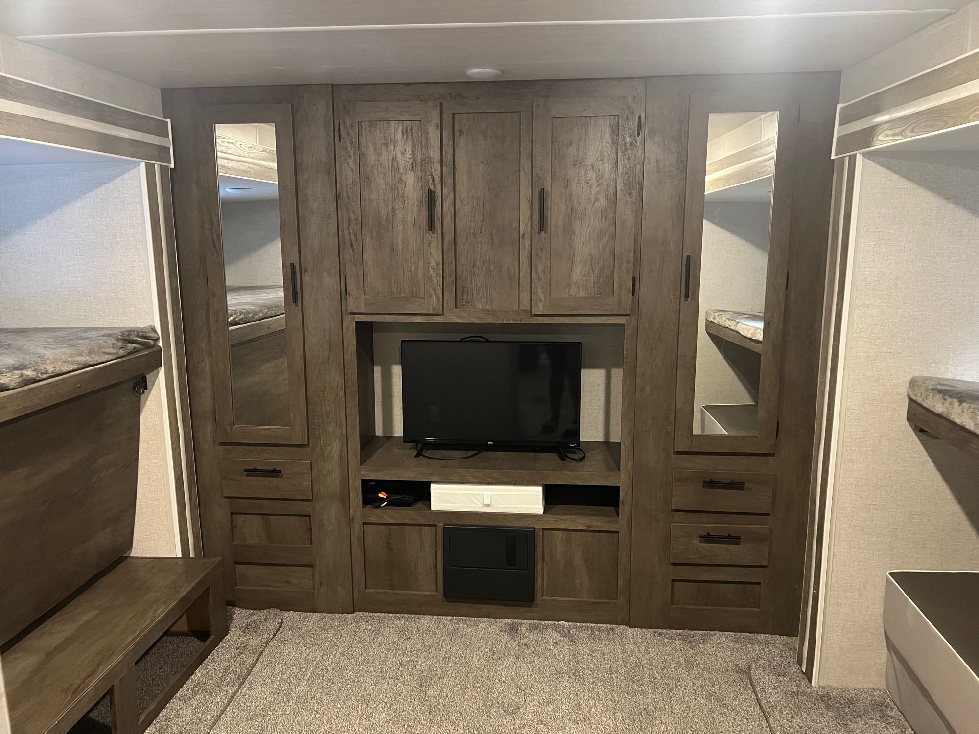 RV rental interior featuring bunk beds, mirrored closets, and entertainment center with TV, providing comfortable sleeping and living space.. Forest River Wildwood 2021