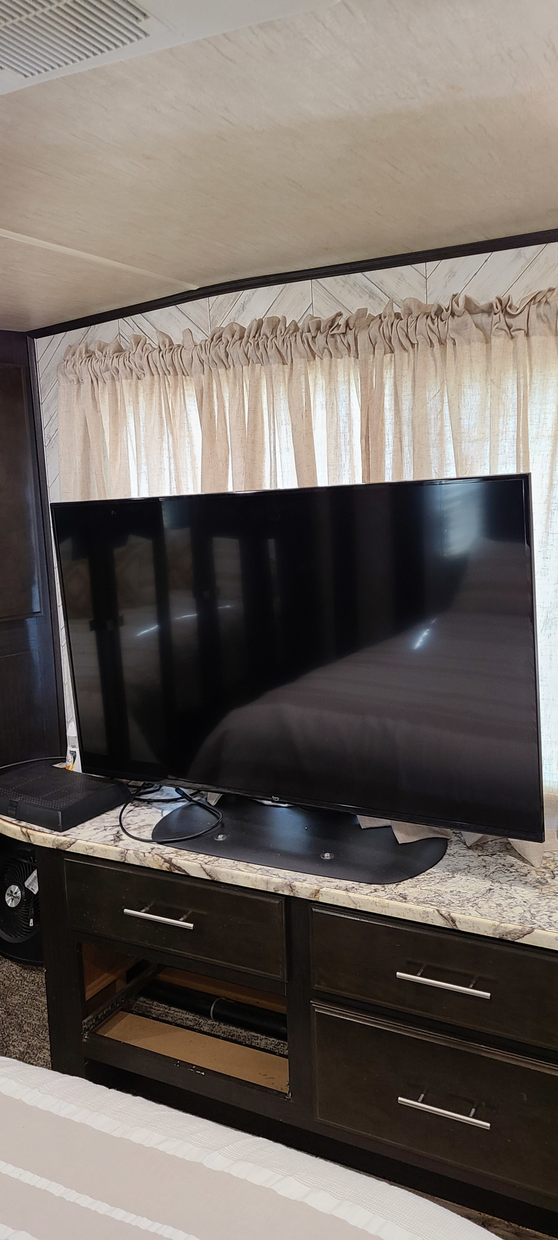 Spacious RV rental bedroom with a large flat-screen TV, modern cabinets, and cozy curtains for your entertainment.. Heartland Road Warrior 2017