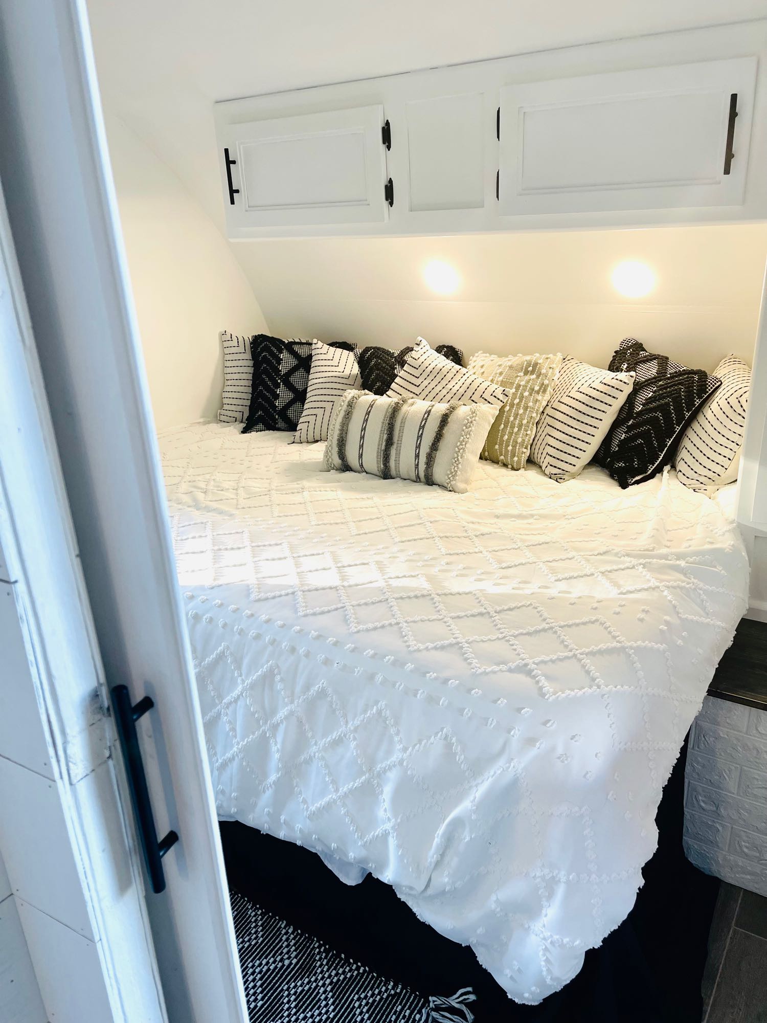 Modern rv rental bedroom interior featuring a cozy white bed with stylish black and white patterned pillows.. Forest River Cherokee Grey Wolf 2019