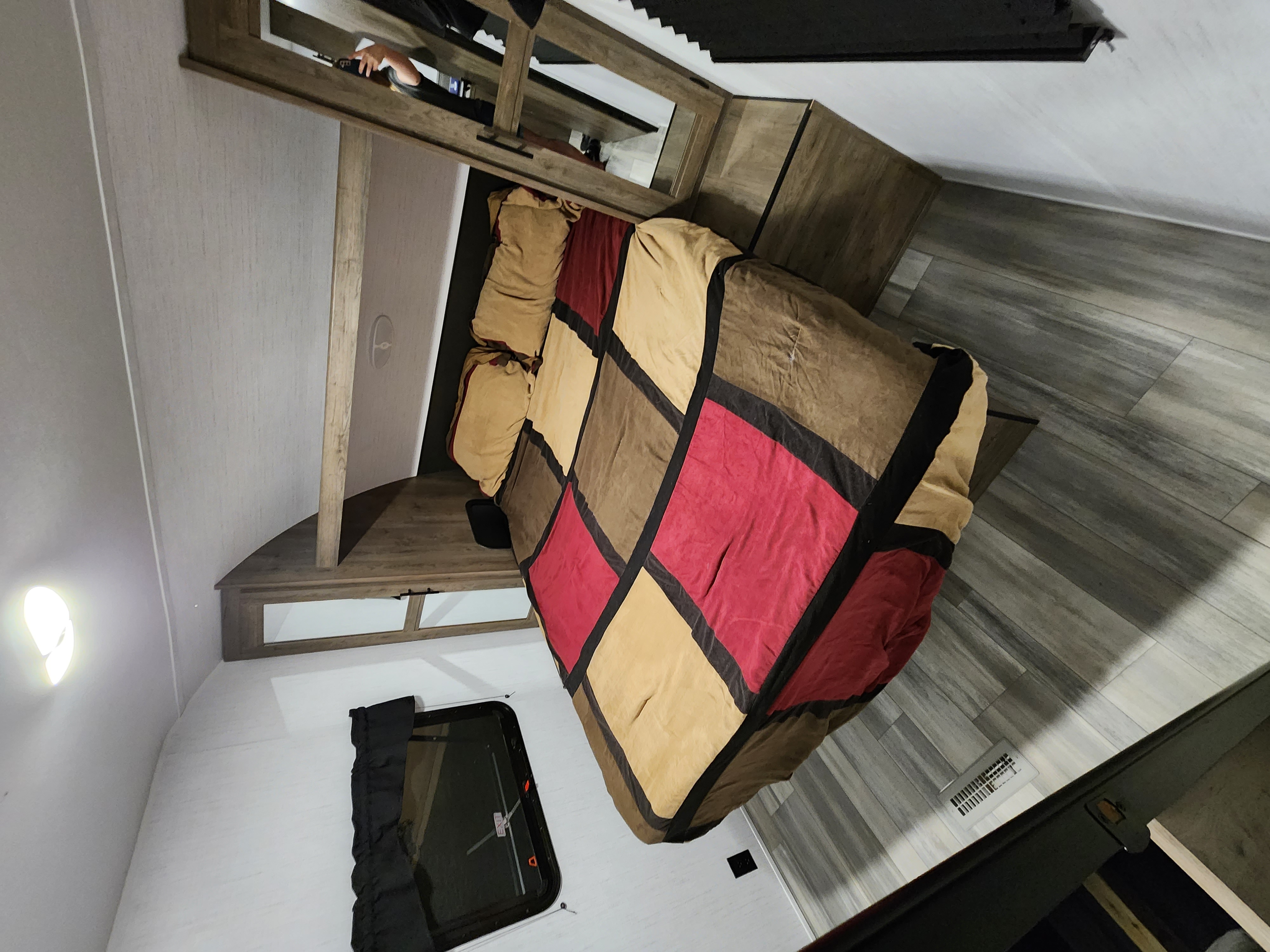 Cozy RV rental bedroom features a patched quilt bed, wood accents, and light-colored walls.. Heartland RV Pioneer 2023