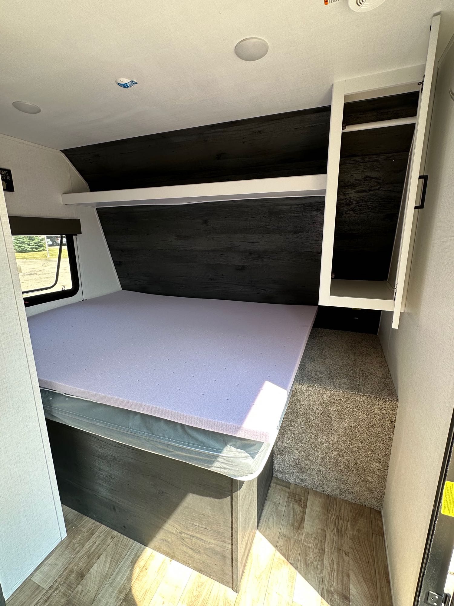Explore this cozy RV rental bedroom. Features include a bed with purple foam topper, storage, and modern interior design.. Keystone RV Hideout 2022