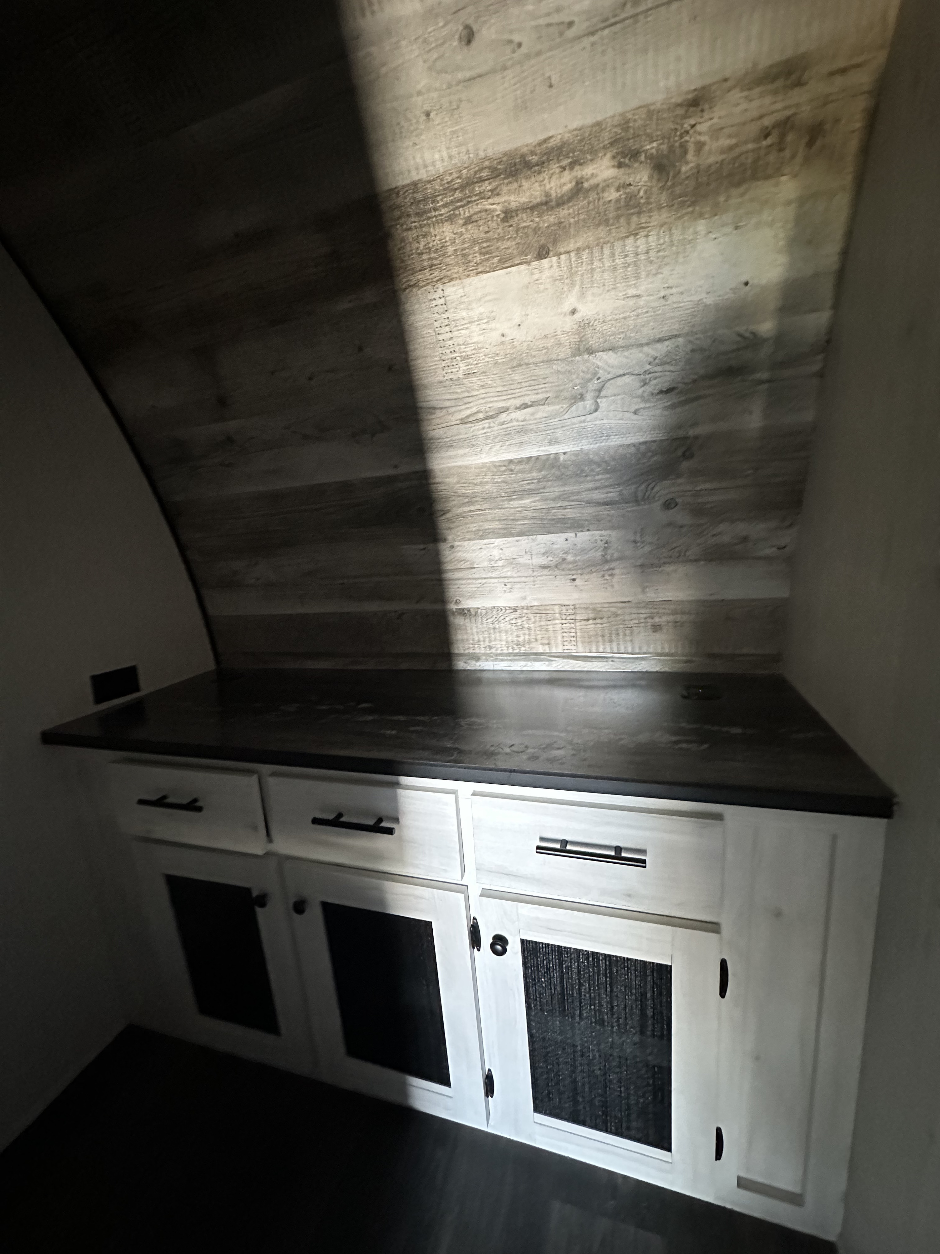 RV rental interior featuring light-colored cabinetry with dark countertop, and a curved, wood-paneled wall/ceiling.. Heartland Lithium 2515S 2022