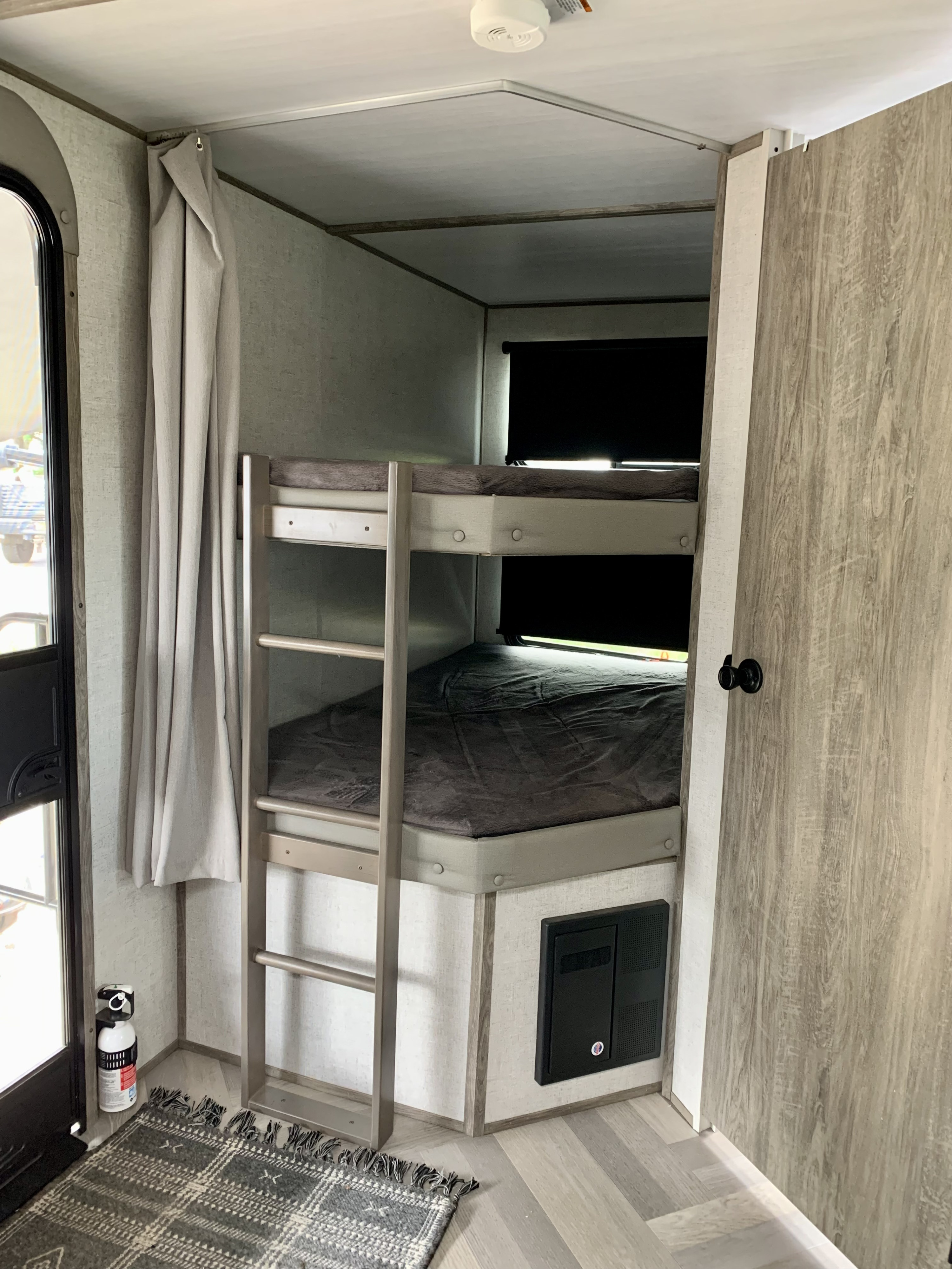 This RV rental interior features sturdy bunk beds with dark bedding, ladder access, and an electrical panel, optimizing compact living space.. Forest River Salem Hemisphere HL 2021