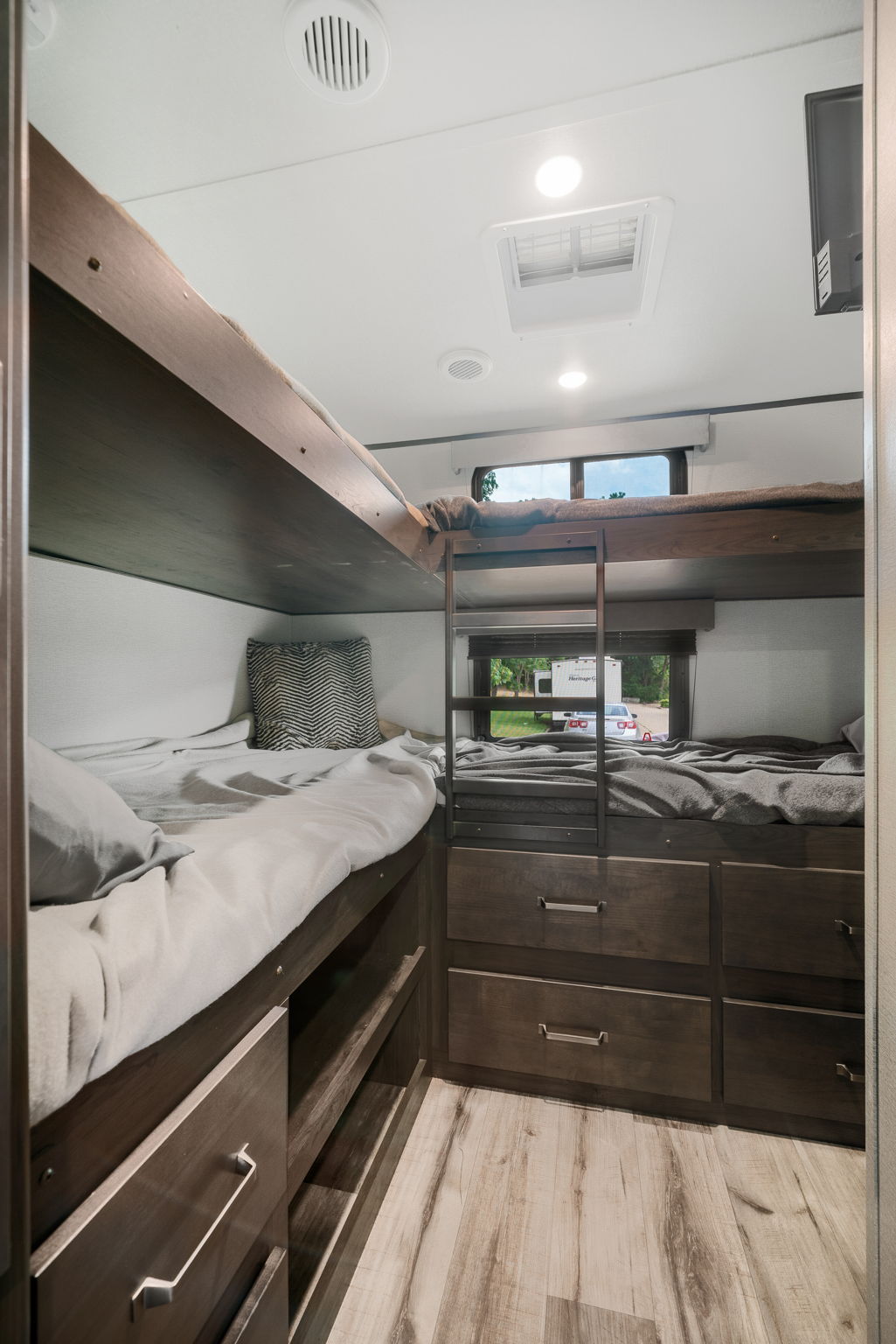 Cozy RV rental bunk room featuring stacked beds, a ladder, ample storage drawers, and scenic windows.. Grand Design Transcend Xplor 2022