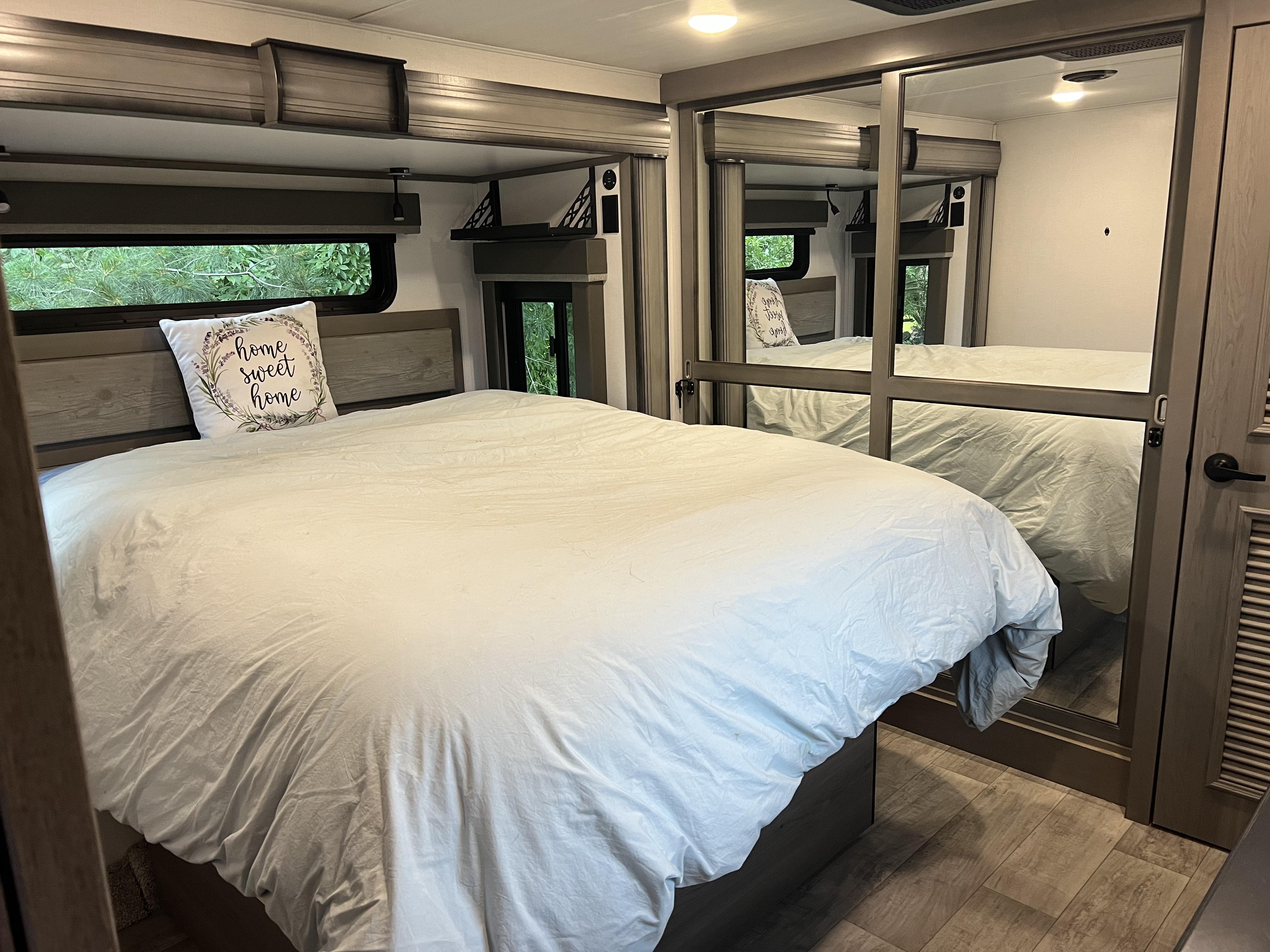 Spacious, cozy RV rental bedroom with white bedding, 'home sweet home' pillow, mirrored closets, and large windows.. Keystone RV Montana Legacy Edition 2022