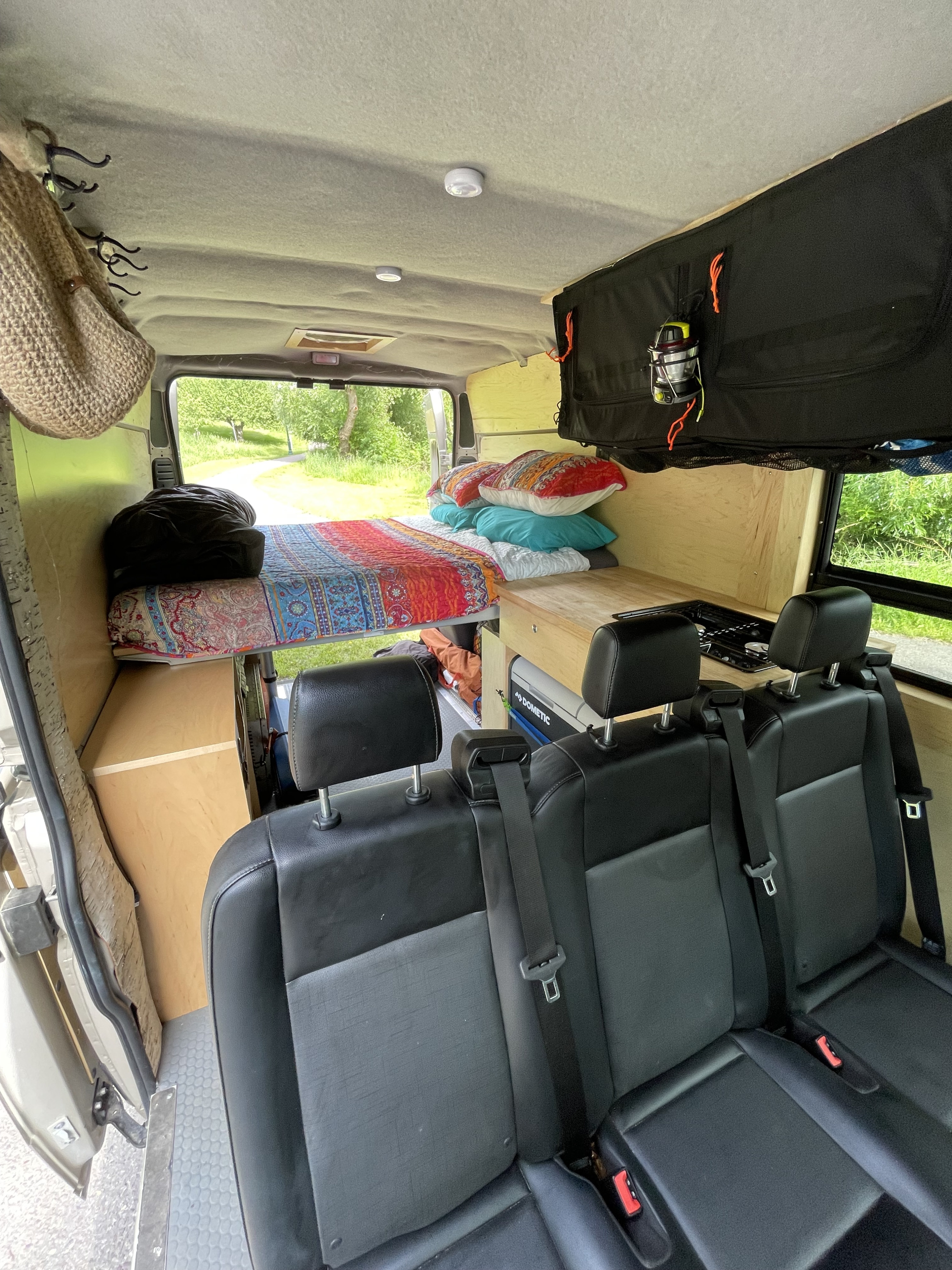 Inside this RV rental, a cozy camper van conversion with a bed, compact kitchen, and passenger seats for adventurous trips.. Custom Camper 2016