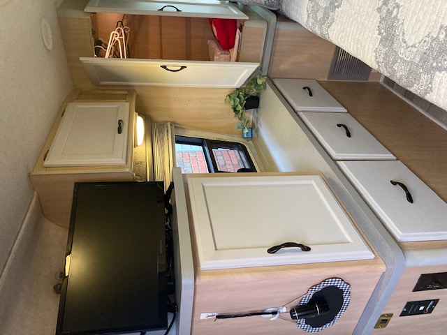 RV rental interior: light wood cabinetry, ample storage, a bed, and TV. Ideal for cozy travels.. Winnebago Rialta 1998