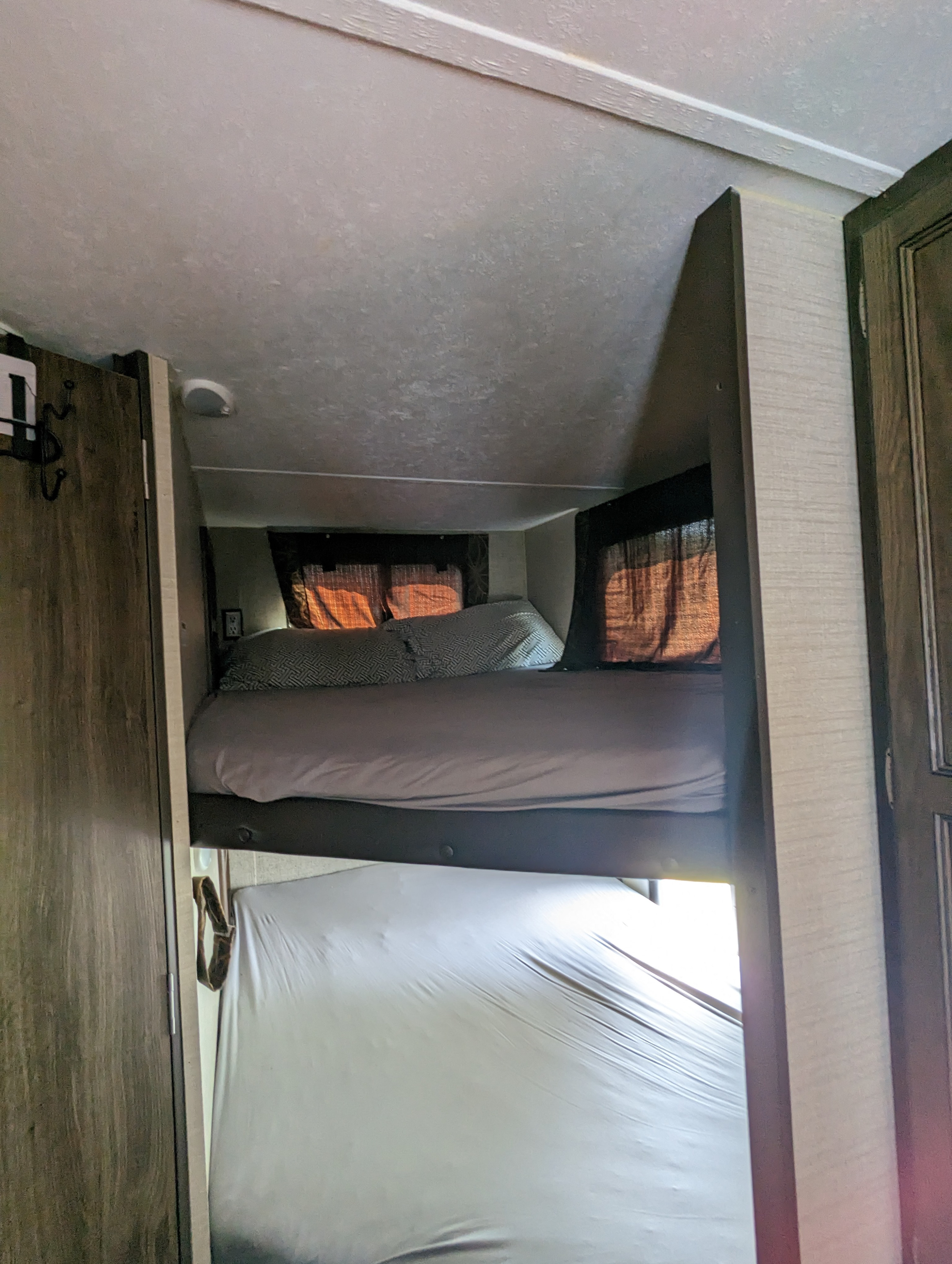 RV rental interior featuring a top bunk bed with patterned pillows and a lower bunk, ideal for compact sleeping arrangements.. Keystone RV Bullet Ultra Lite 2017