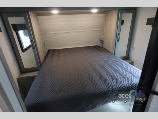This RV rental bedroom offers a comfortable bed, mirrored wardrobes, and a window, providing a cozy space for travel.. Dutchmen Kodiak Ultra Lite 2022