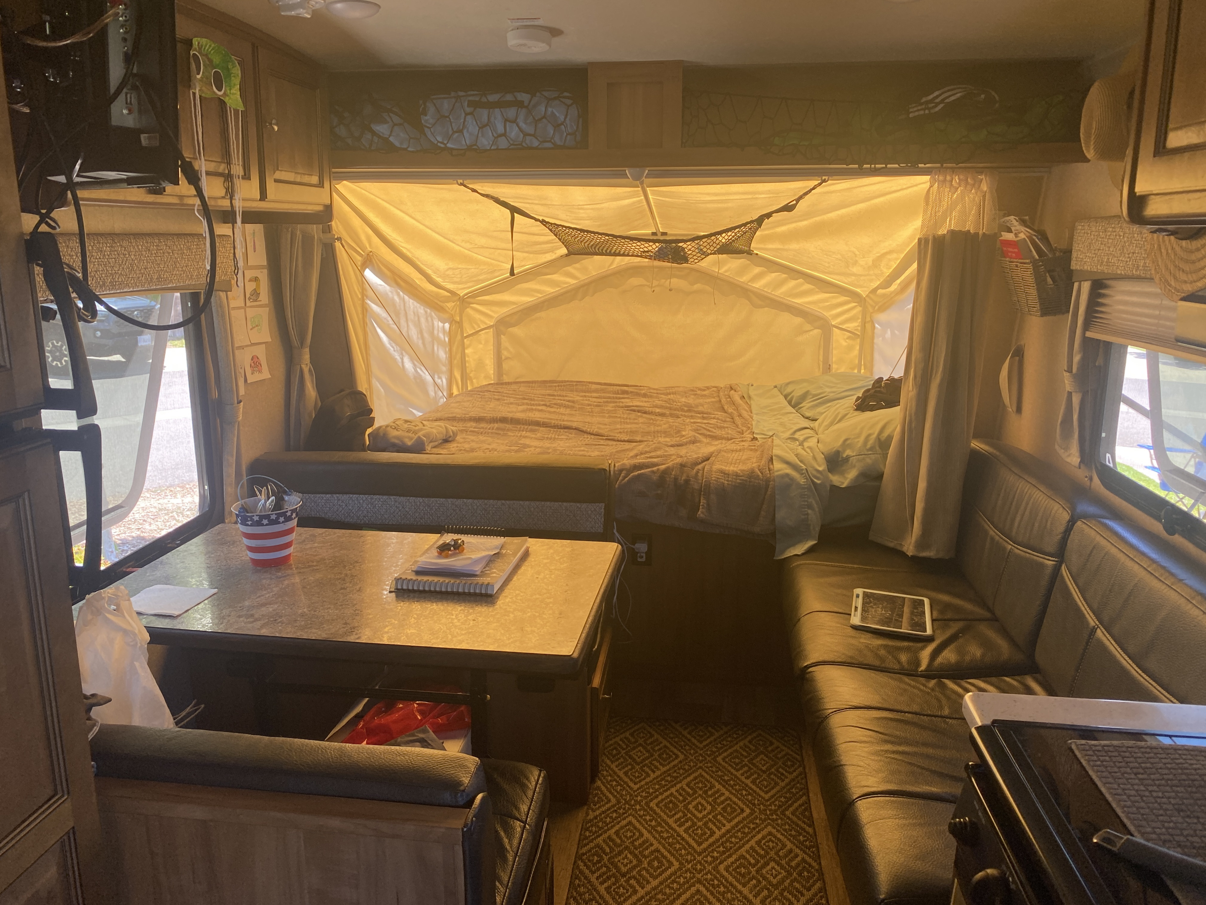Cozy rv rental interior featuring a convertible bed, dining table, and living area. Ideal for family road trips.. Forest River Rockwood Roo 2018