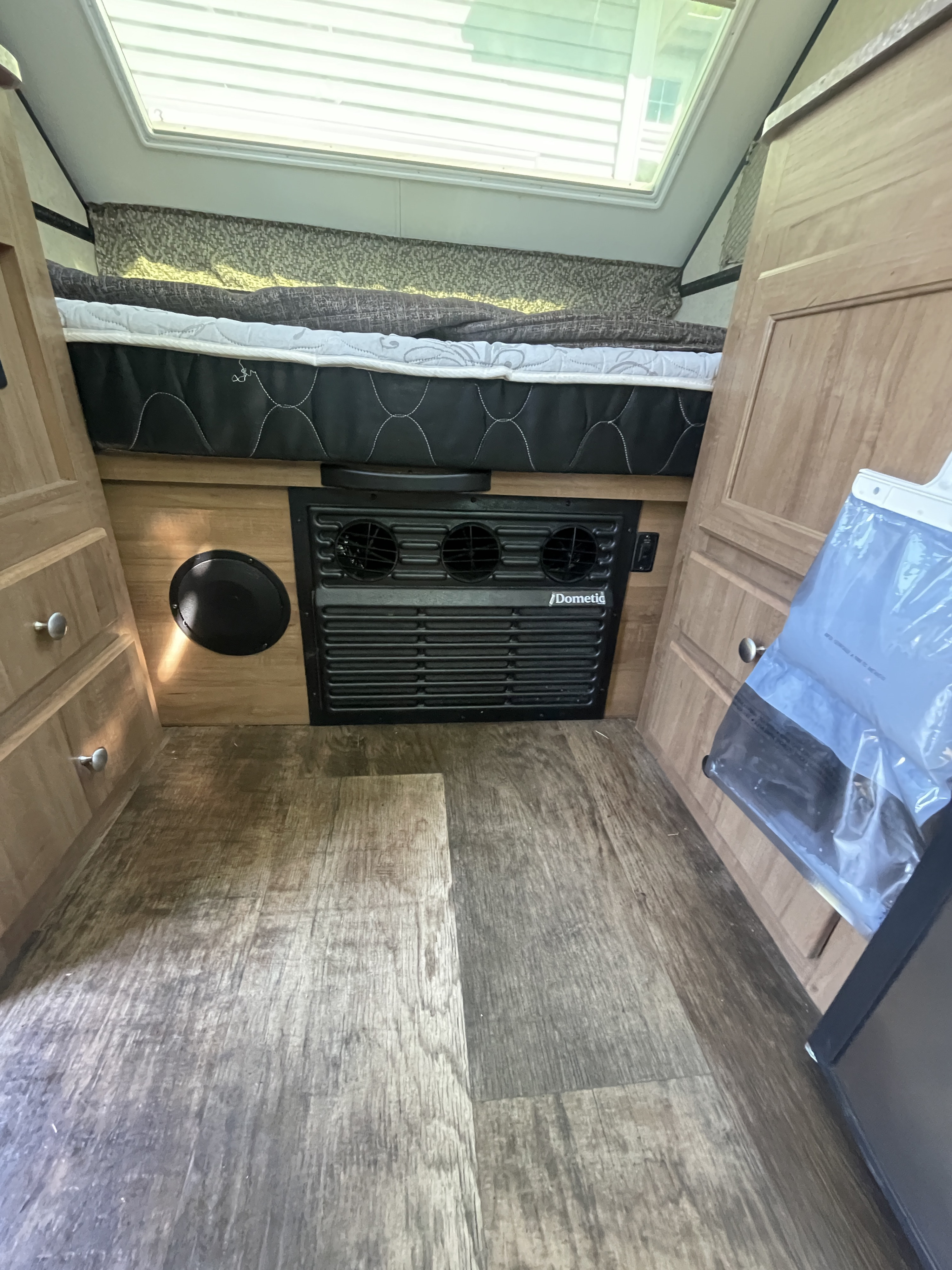 RV rental interior: A compact sleeping area with bed, Dometic climate unit, and wood-look floor. Ready for travel.. Forest River Rockwood Premier 2018