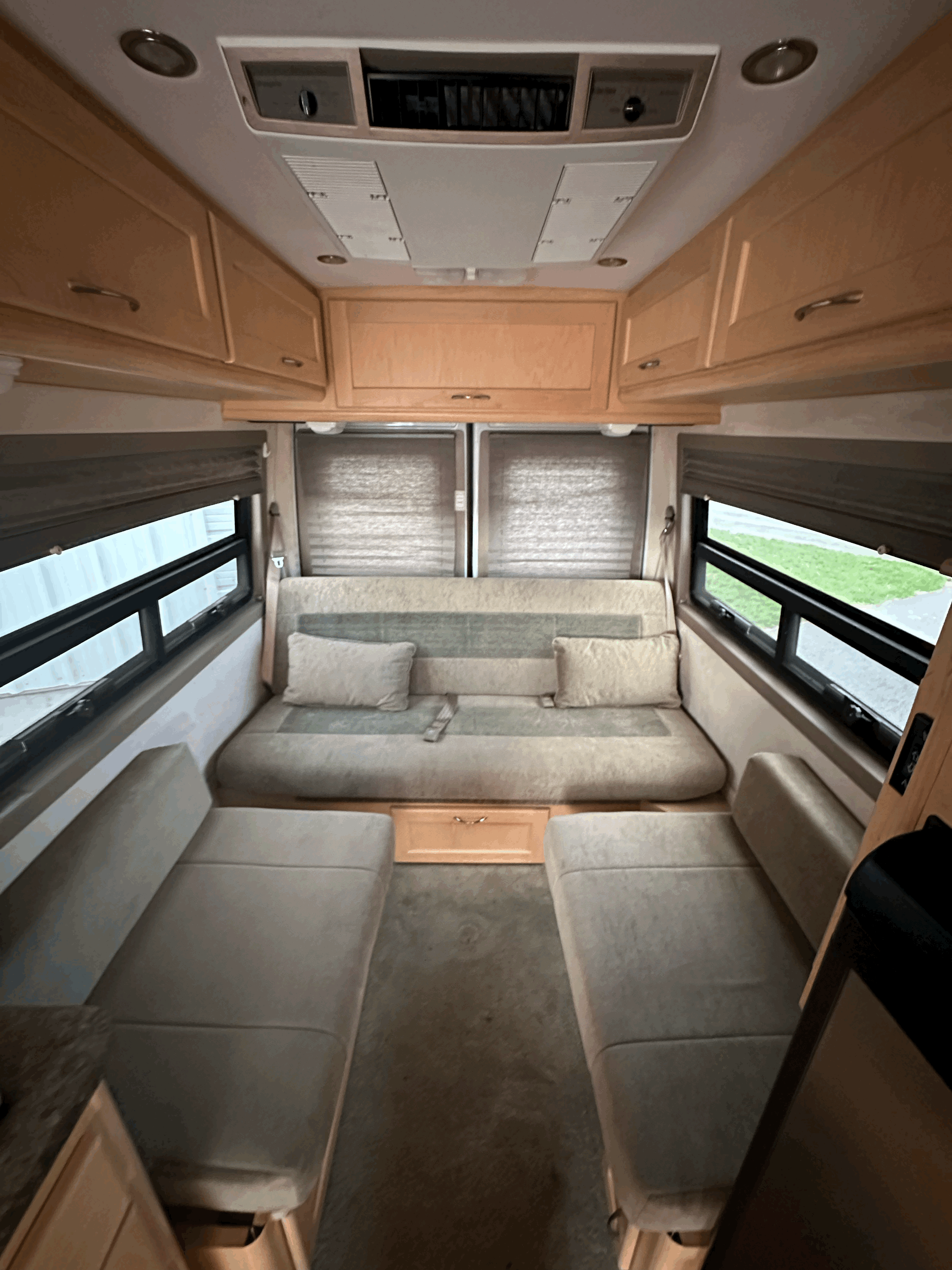 RV rental's inviting interior: featuring a versatile sofa bed, two separate seats, wood cabinets, and large windows.. Pleasure-Way Pleasure-Way Class B 2005