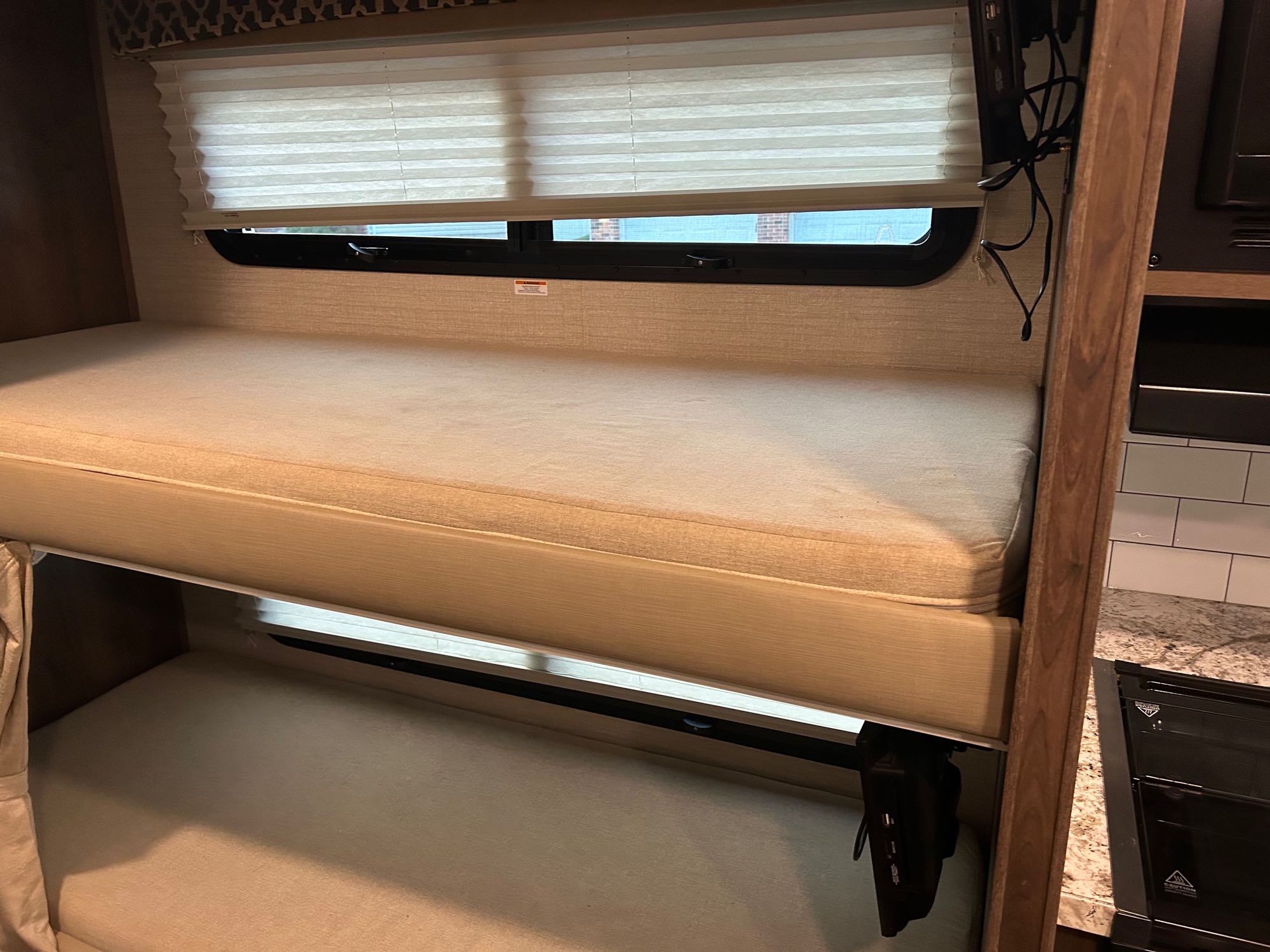 RV rental: Bright interior featuring comfy stacked bunk beds with mattresses, a window, and a kitchen glimpse.. Jayco Redhawk 2020