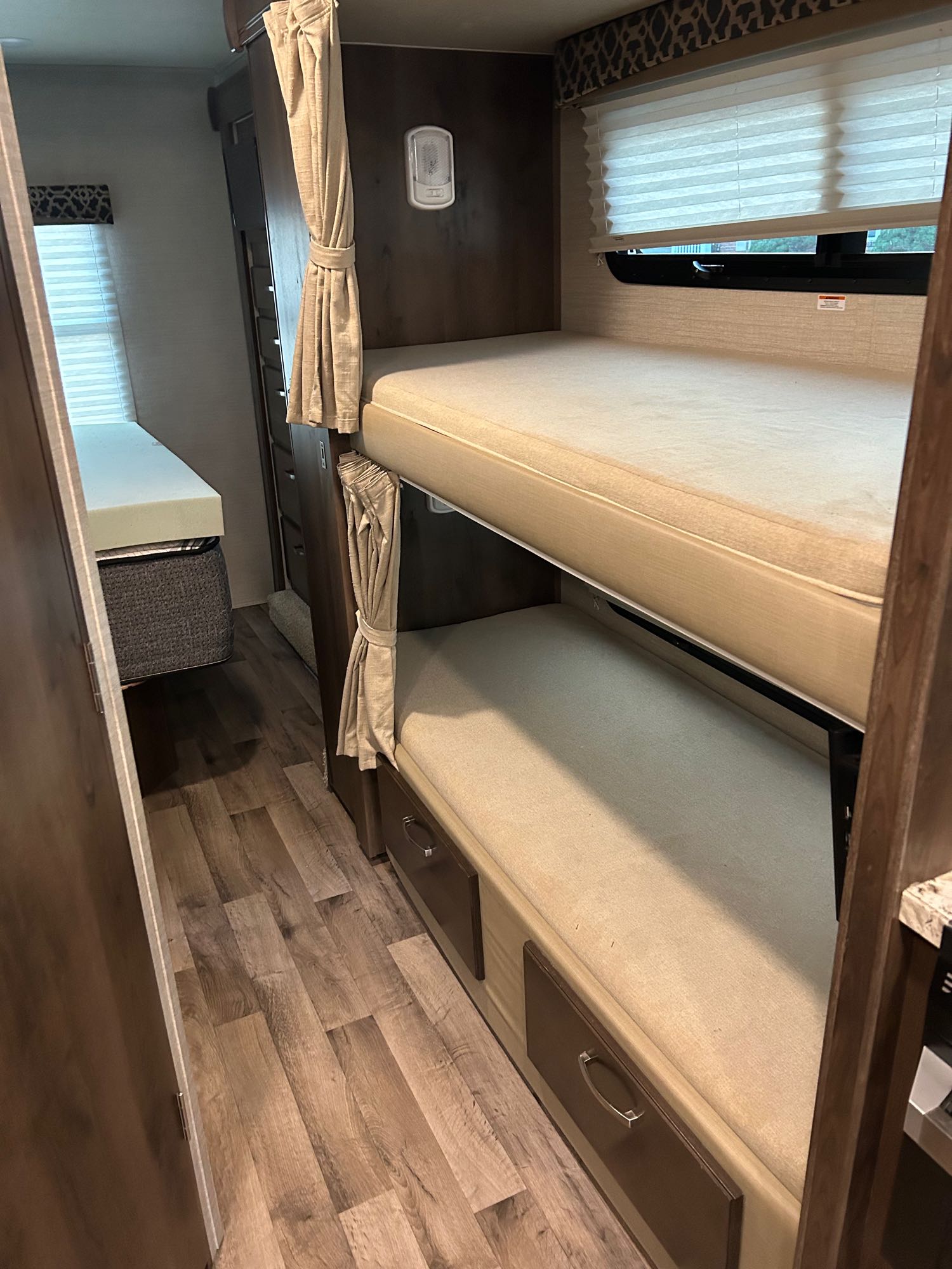 RV rental interior: bunk beds with curtains, lower storage drawers, and a separate windowed sleeping area with a wood floor.. Jayco Redhawk 2020