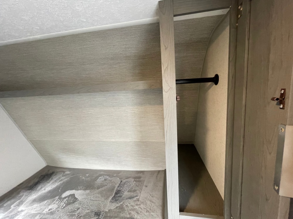 RV rental interior: A compact closet with a clothes hanging rod and wood-grain panels, perfect for storage.. Forest River Ozark 2023