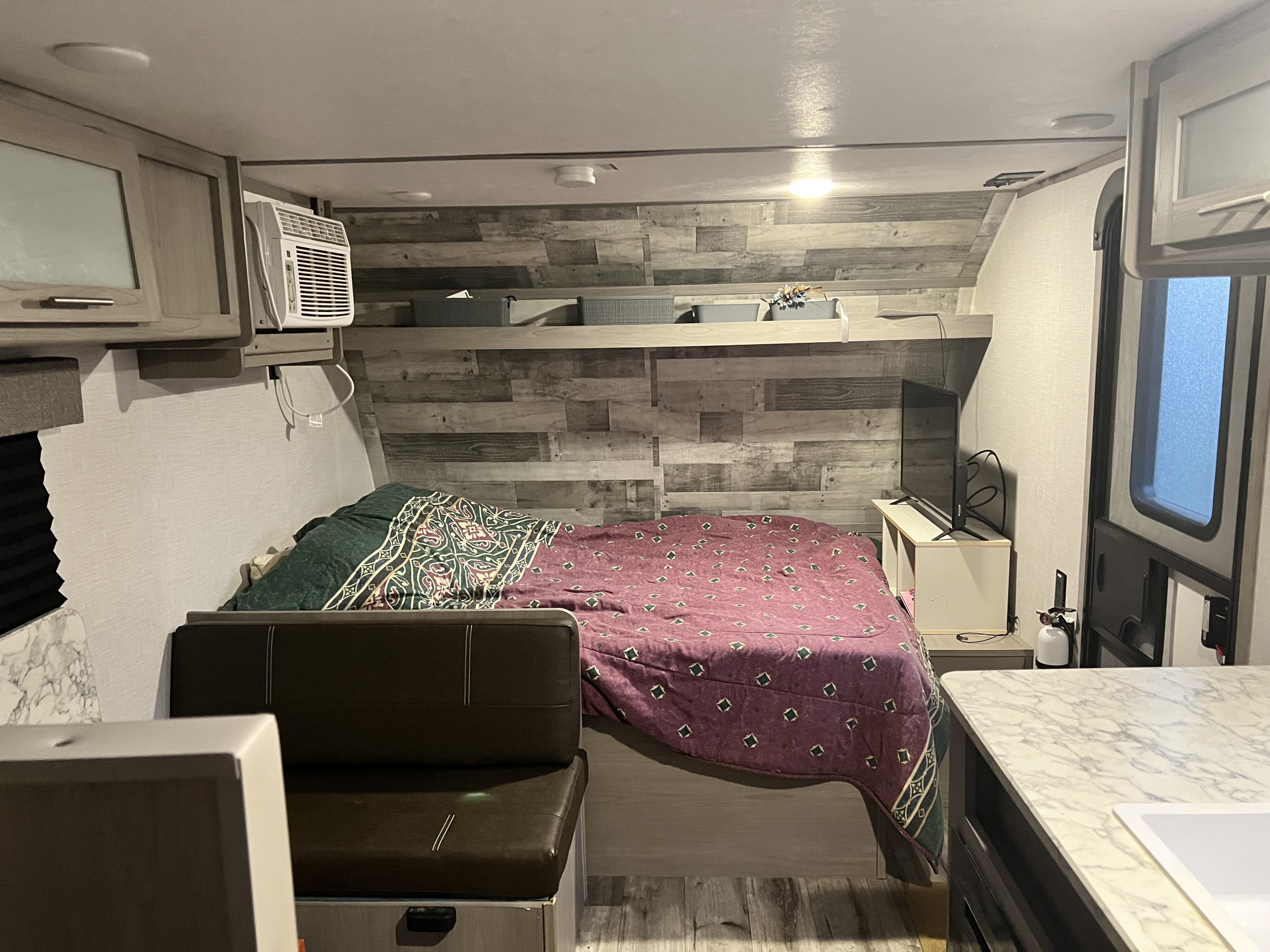 This cozy rv rental interior features a comfortable bed, dinette, AC unit, and TV setup, ideal for travel trailer adventures.. Dutchmen Coleman Lantern LT 2022