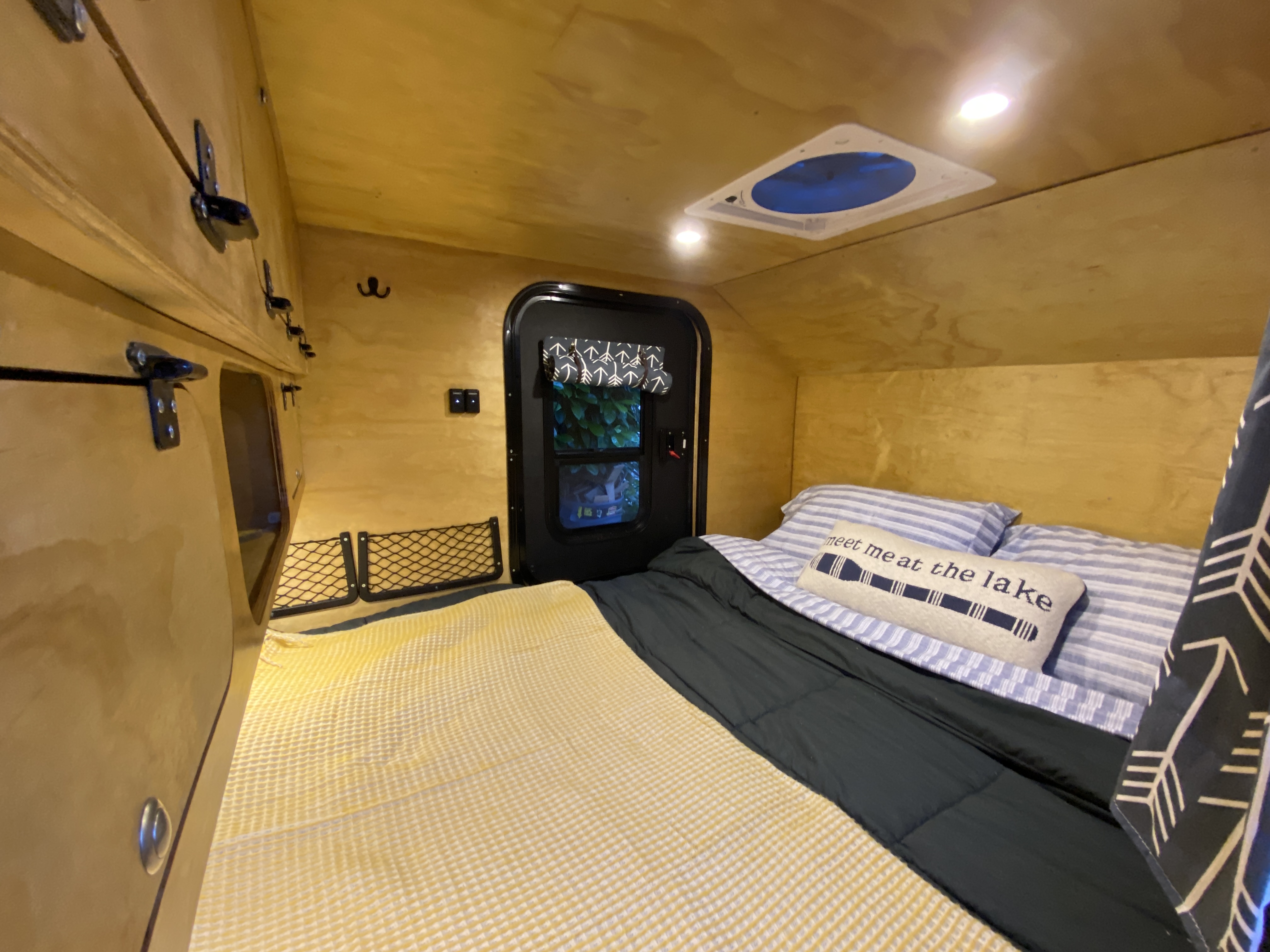 Experience a cozy RV rental interior, featuring a comfortable bed, wooden walls, overhead storage, and a ceiling fan.. U-Bilt U-Bilt 2021