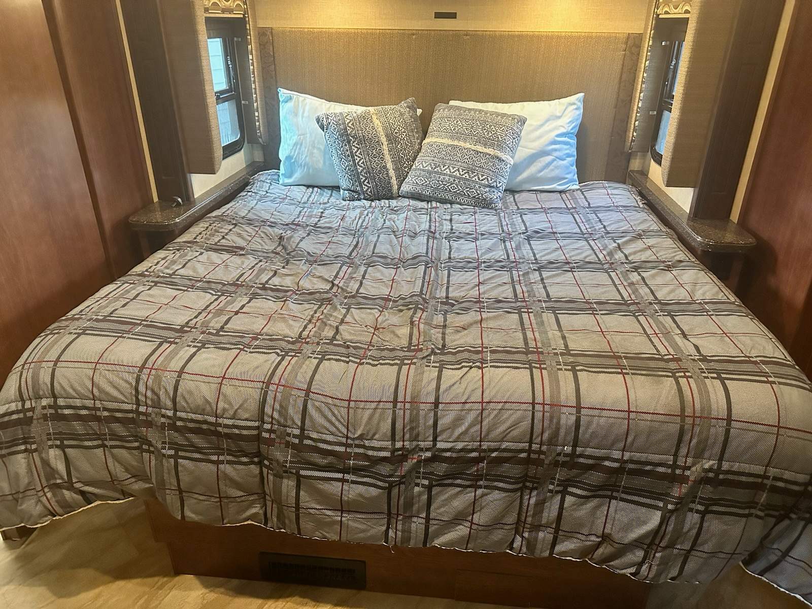 Comfortable RV rental bedroom featuring a plaid bed with pillows, ideal for a cozy mobile retreat.. Fleetwood Bounder 36H 2017