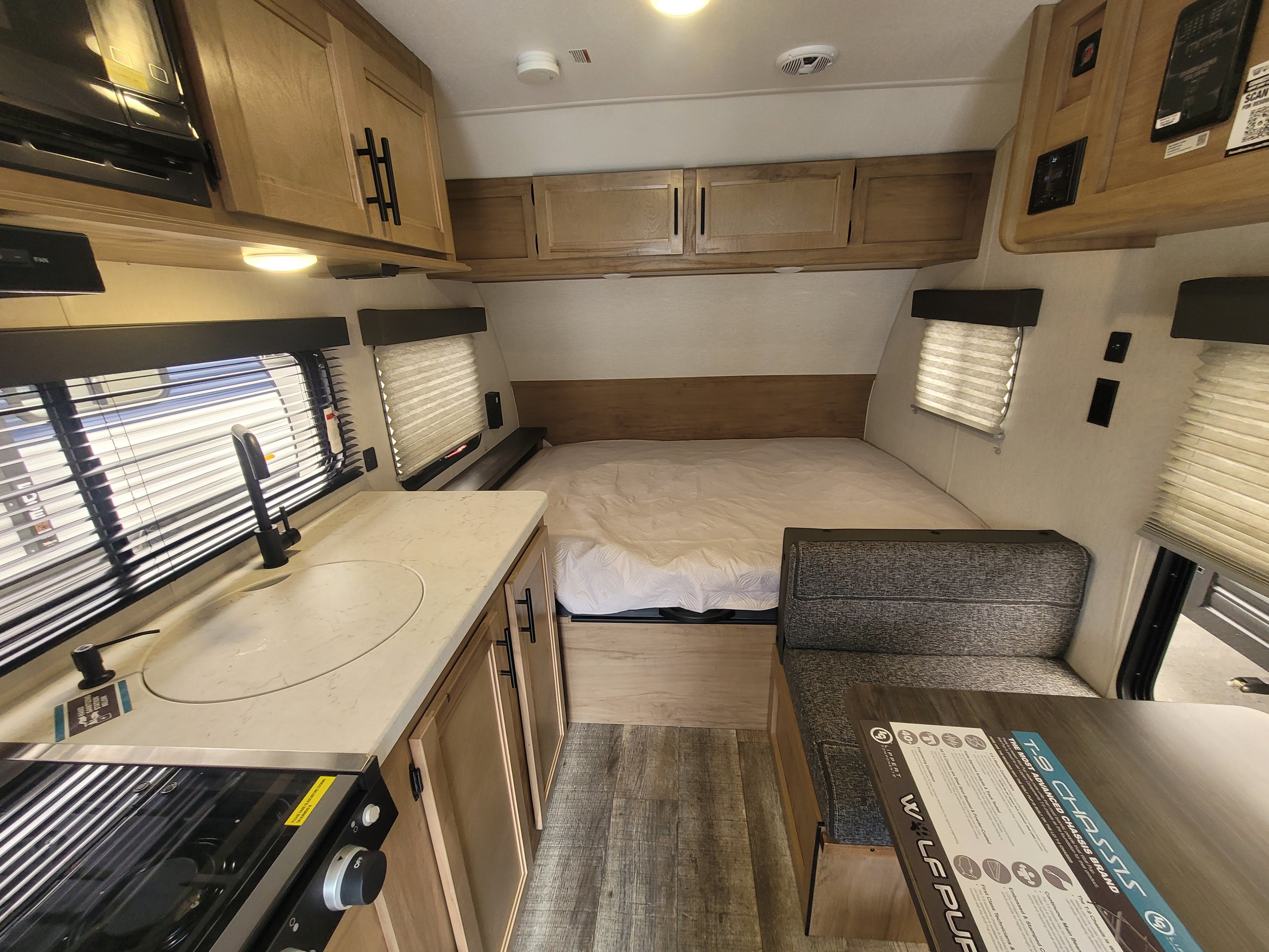 Bright RV rental interior showing a compact kitchen, cozy bed, and dinette. Ideal for adventures.. Forest River Cherokee Grey Wolf 2023