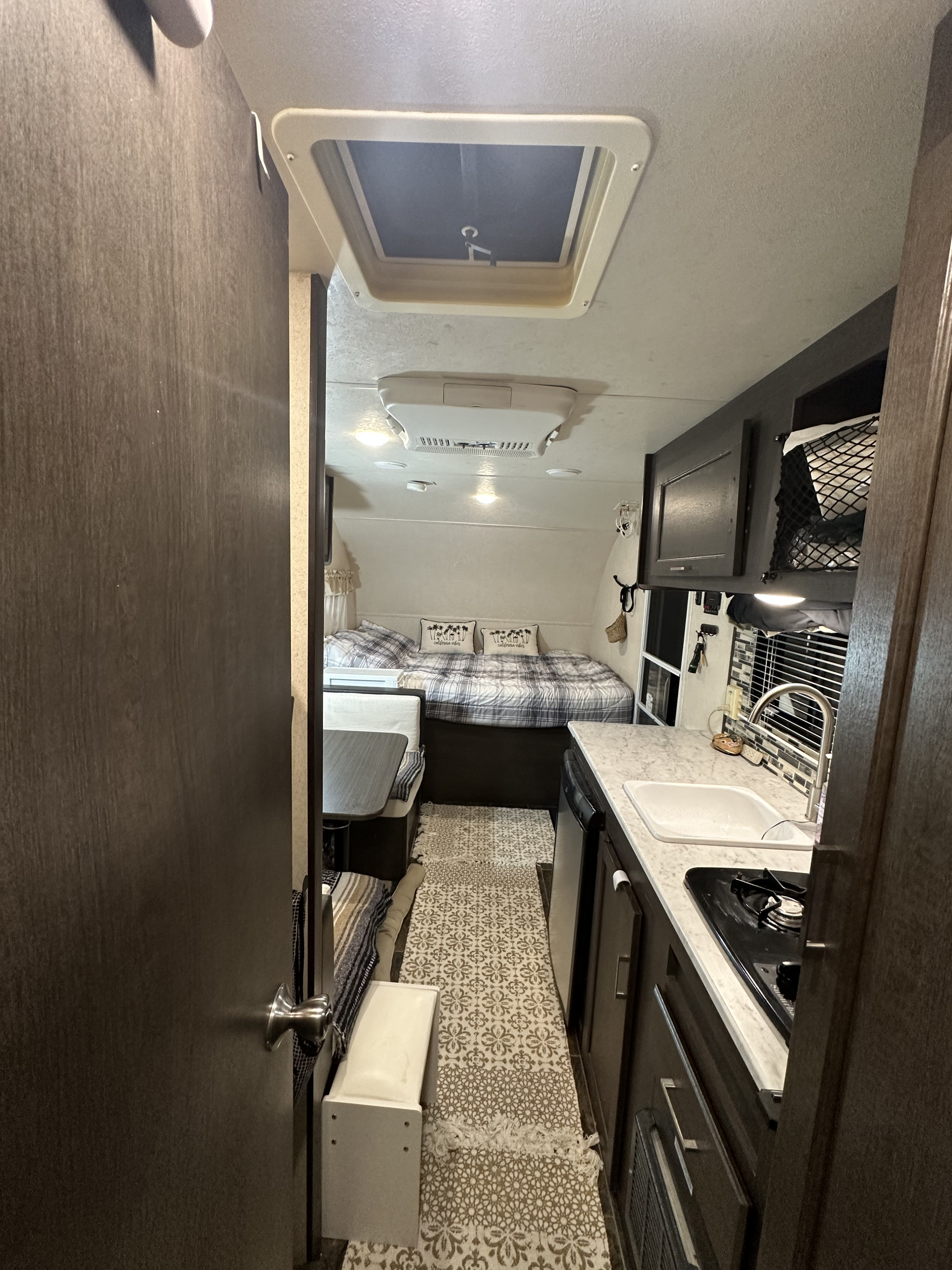 Cozy RV rental interior with a compact kitchen, bed, and dinette area.. Forest River Evo 2019