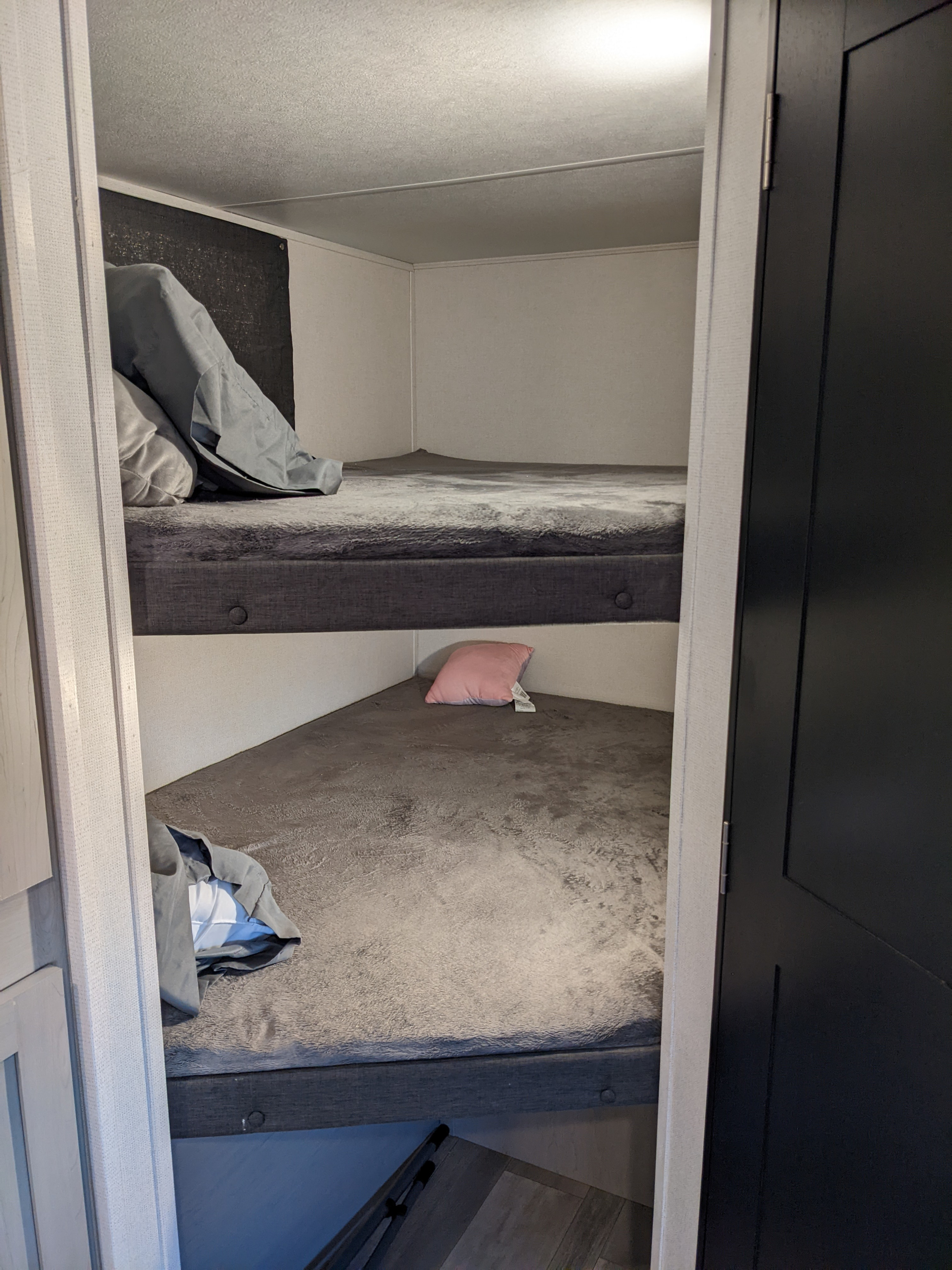 RV rental: two stacked bunk beds with soft grey bedding. A pink pillow is on the lower bunk, offering comfortable sleeping.. PrimeTime Tracer 2022