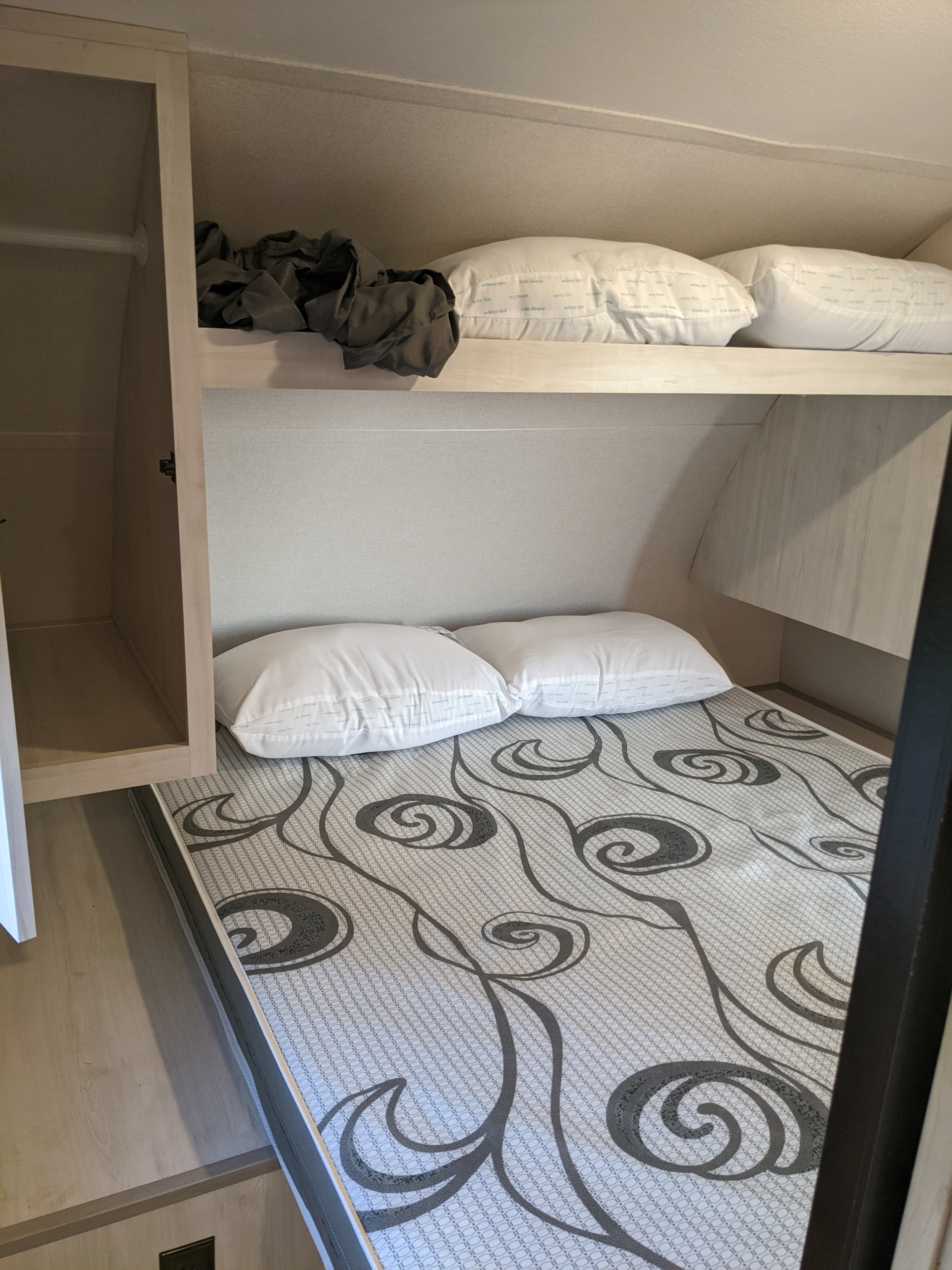 RV rental bunk bedroom: Cozy sleeping area with patterned mattress, pillows, and built-in storage.. PrimeTime Tracer 2022