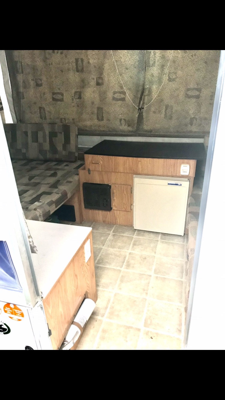 Compact RV rental interior: cozy bed, kitchenette with mini-fridge, and heater for comfy travels.. Jayco Qwest 2006