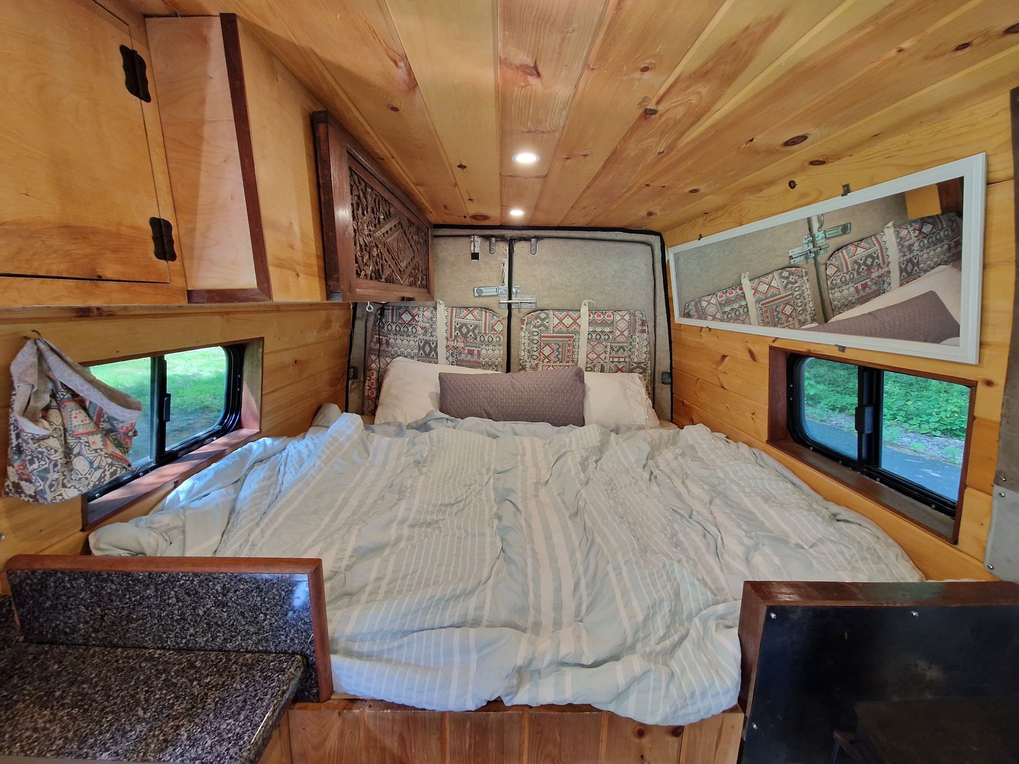 An inviting RV rental interior with a cozy bed, natural wood walls & ceiling, and handy storage for your next adventure.. Dodge Sprinter Cargo 2006