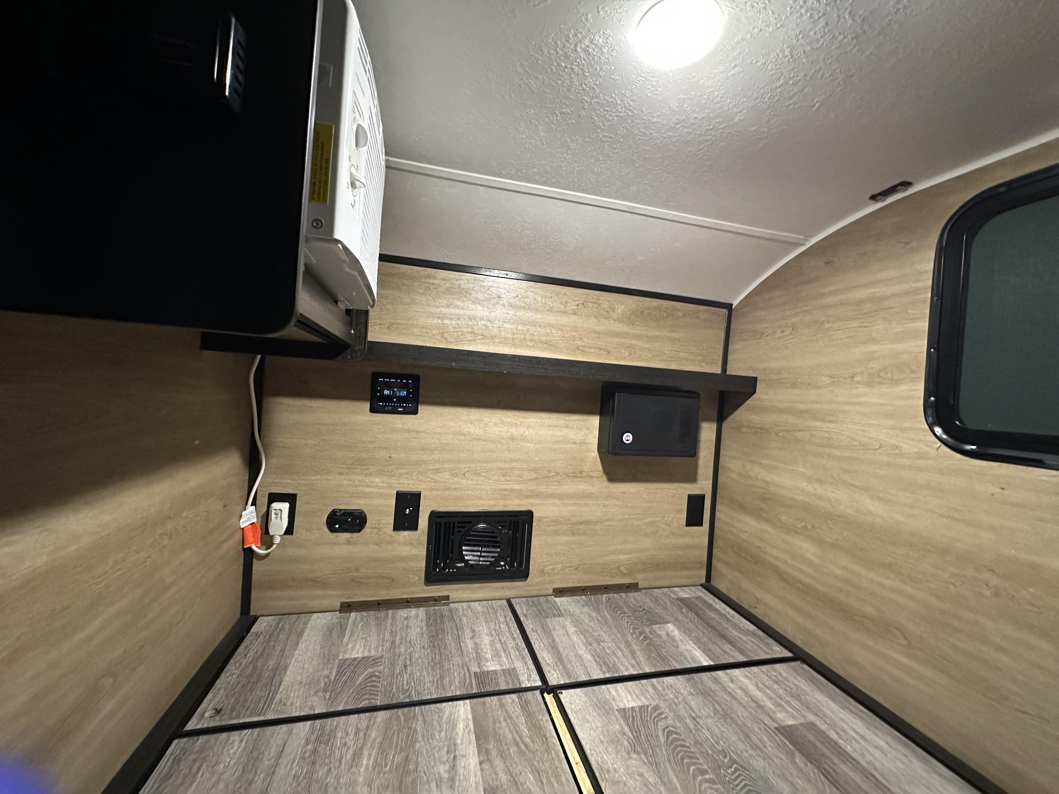 RV rental interior: compact sleeping area with a window, mounted AC, control panel, and essential outlets.. Braxton Creek Bushwhacker 2021