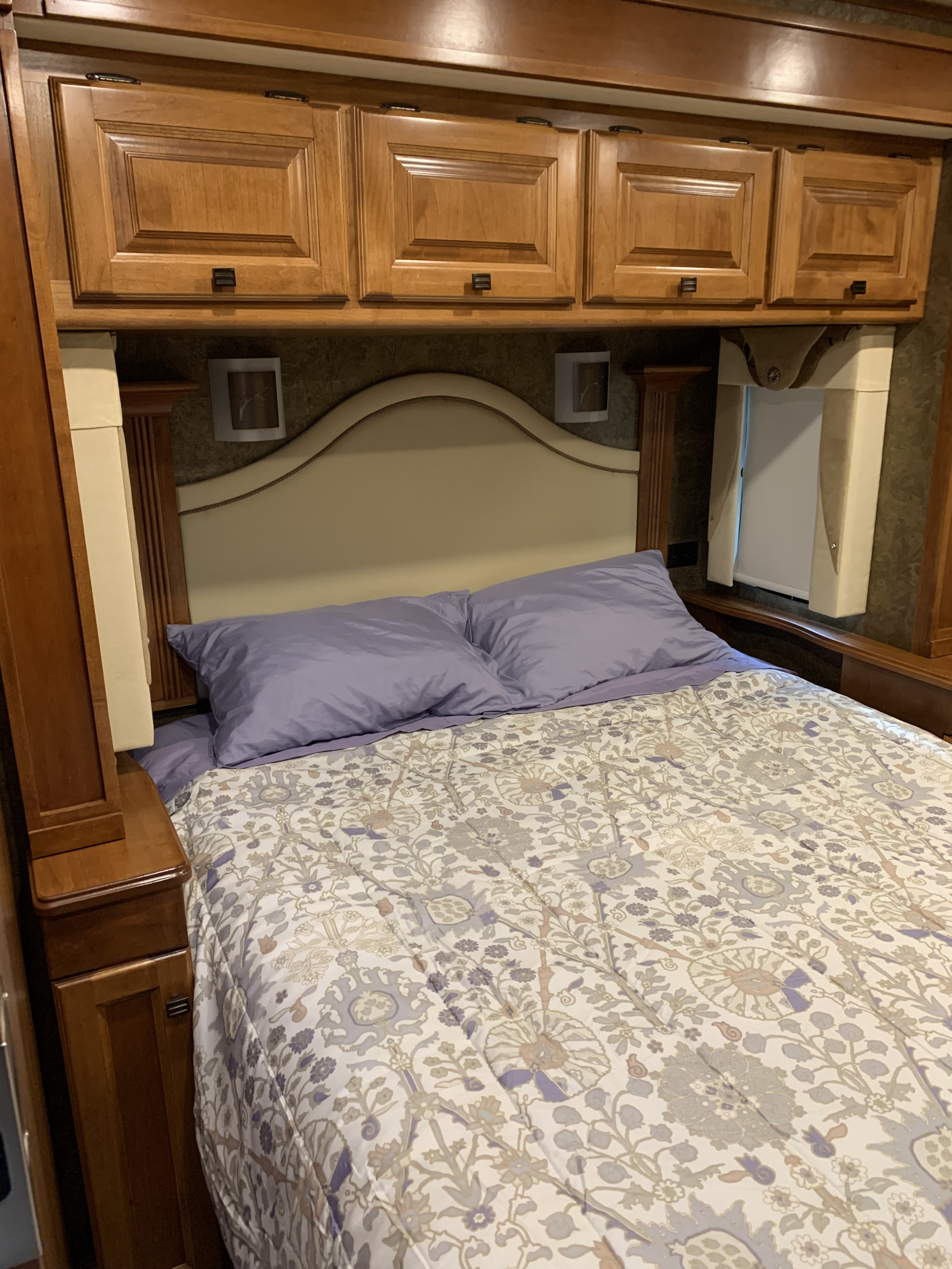 Comfortable RV rental bedroom with wooden cabinets, a padded headboard, and floral patterned bedding.. Allegro Allegro Motorhome 2014