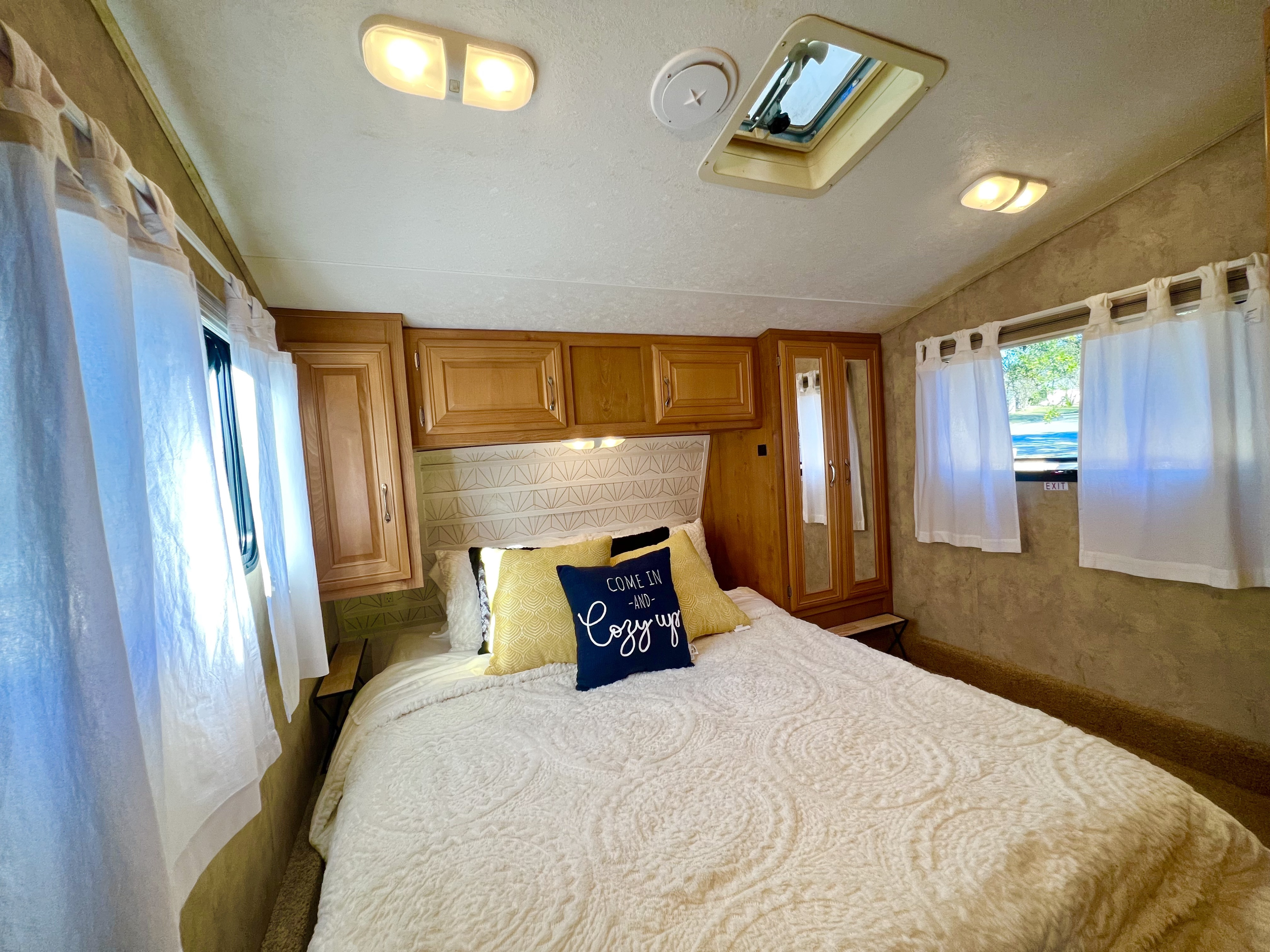Cozy RV rental bedroom with comfortable queen bed, wood cabinets, sunny windows, and a ceiling vent for fresh air.. Keystone RV Raptor Toy Hauler 2007