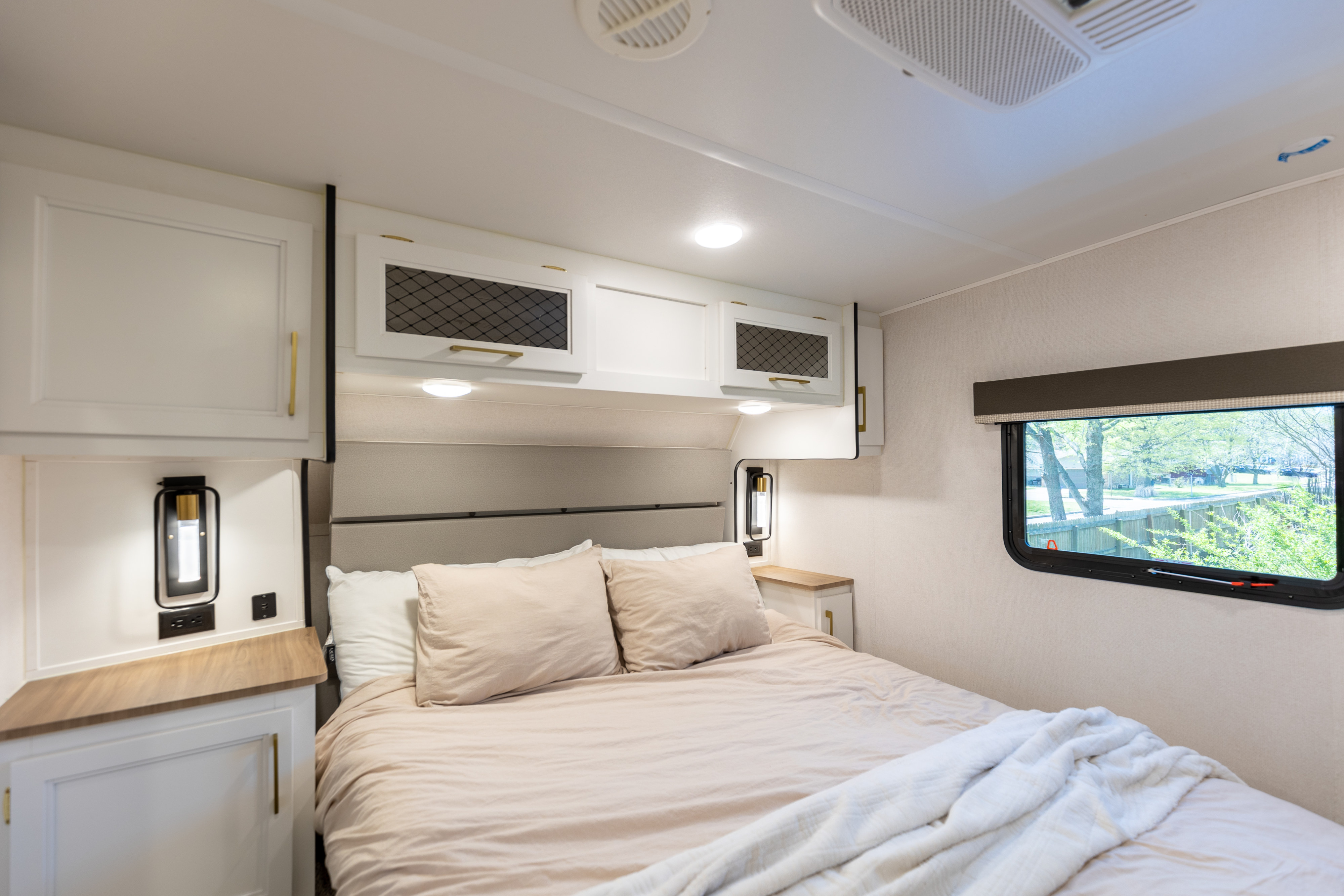 Spacious RV rental bedroom featuring a comfy bed, modern cabinets, bedside lamps, and a scenic window view.. Prime Time Crusader 330MBH 2022