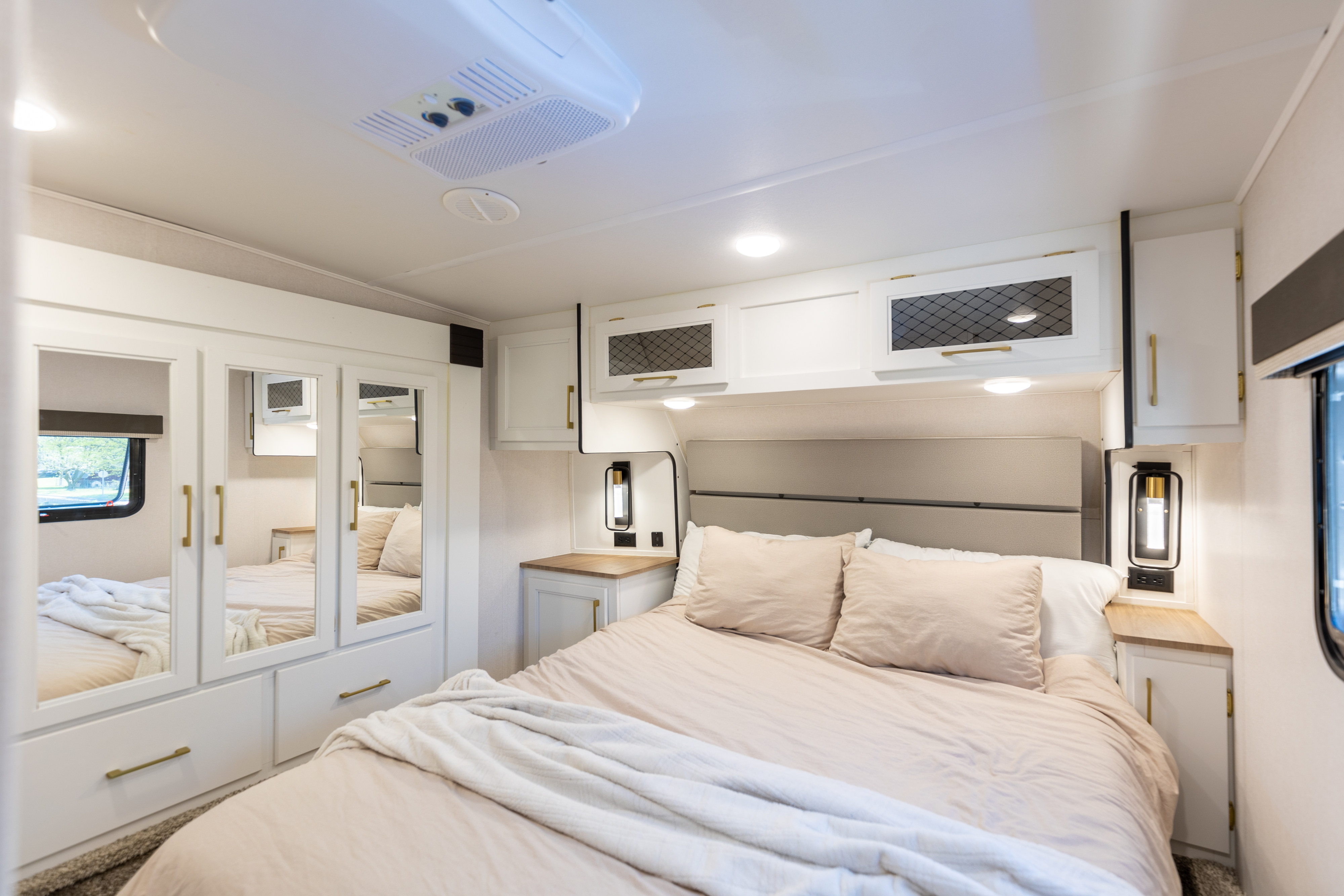 This bright RV rental bedroom features a queen bed, mirrored wardrobe, ample overhead storage, and modern lighting for a comfortable stay.. Prime Time Crusader 330MBH 2022